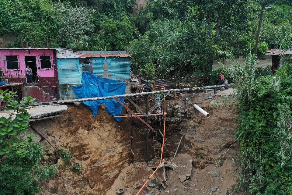 Vecinos de la colonia Cinco de enero, en Villalobos 2, zona 12 de Villa Nueva, deben cruzar por un puente improvisado para llegar a sus casas, pues un socavamiento los dejó incomunicados. (Foto Prensa Libre: María José Bonilla)