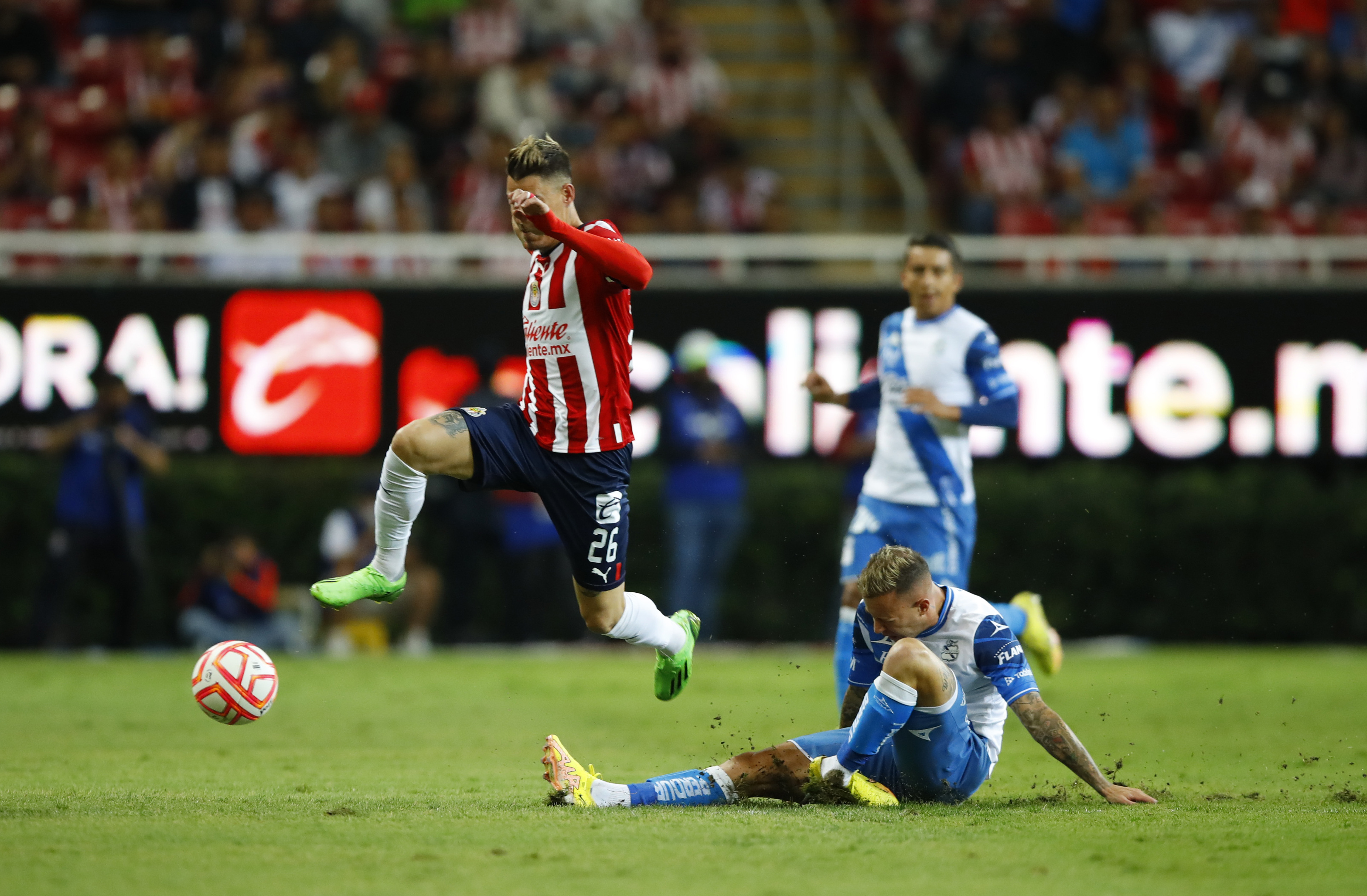 Cristian Calderón (i) del Guadalajara disputa el balón con Gustavo Ferrareis (d) de Puebla quién se lesiona hoy durante un partido de la jornada 14 del torneo Apertura 2022 de la liga del fútbol mexicano, disputado en el Estadio Akron, en Guadalajara, Jalisco (México). Foto Prensa Libre (EFE)