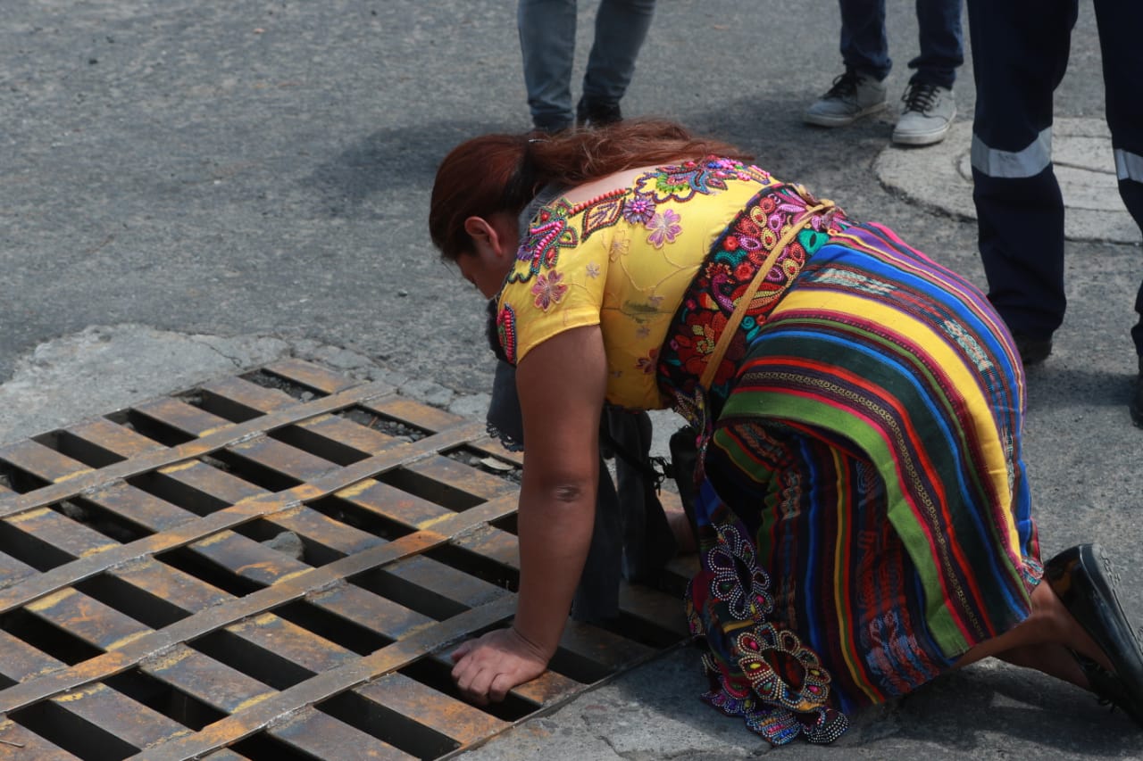 Familiares gritan a sus familiares en una rendija de alcantarillado. (Foto Prensa Libre: María José Bonilla)