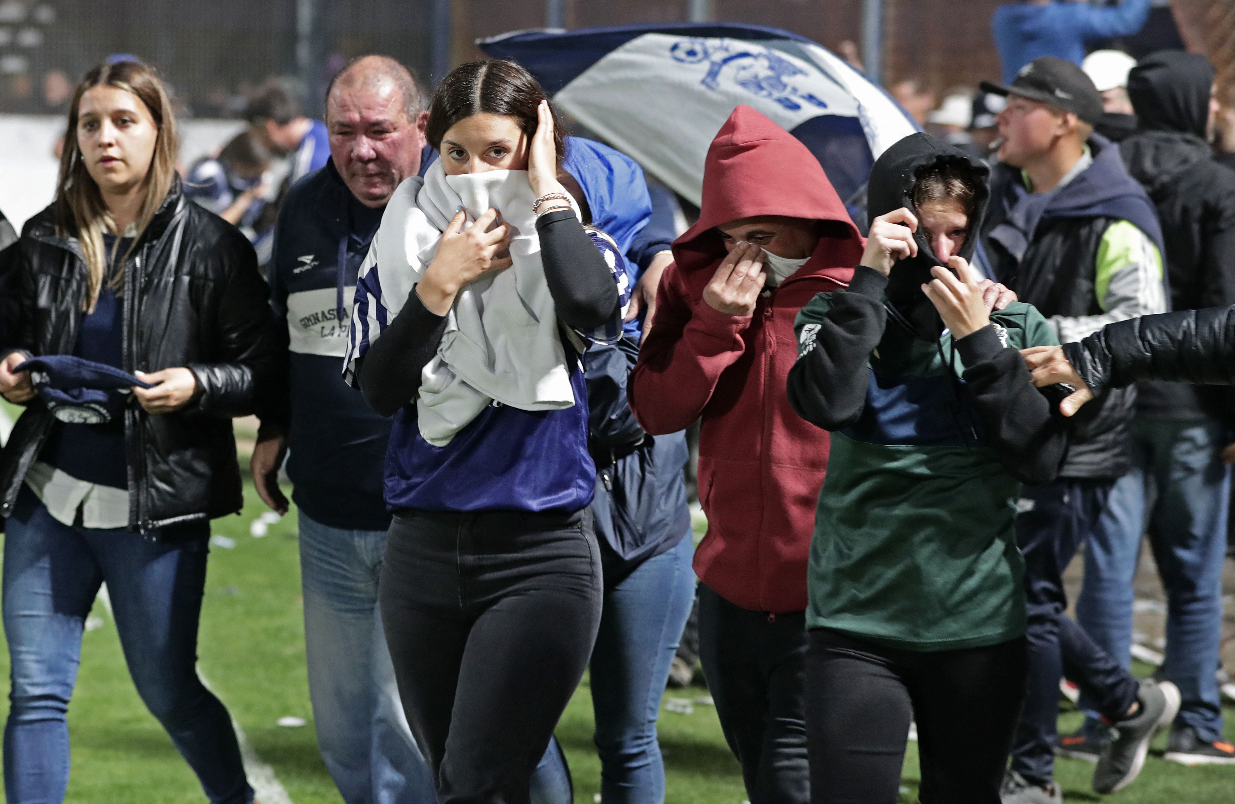 Aficionados de Esgrima se protegen de los gases lanzados por la policía. El partido contra Boca Junior ya no se realizó. (Foto Prensa Libre: AFP)