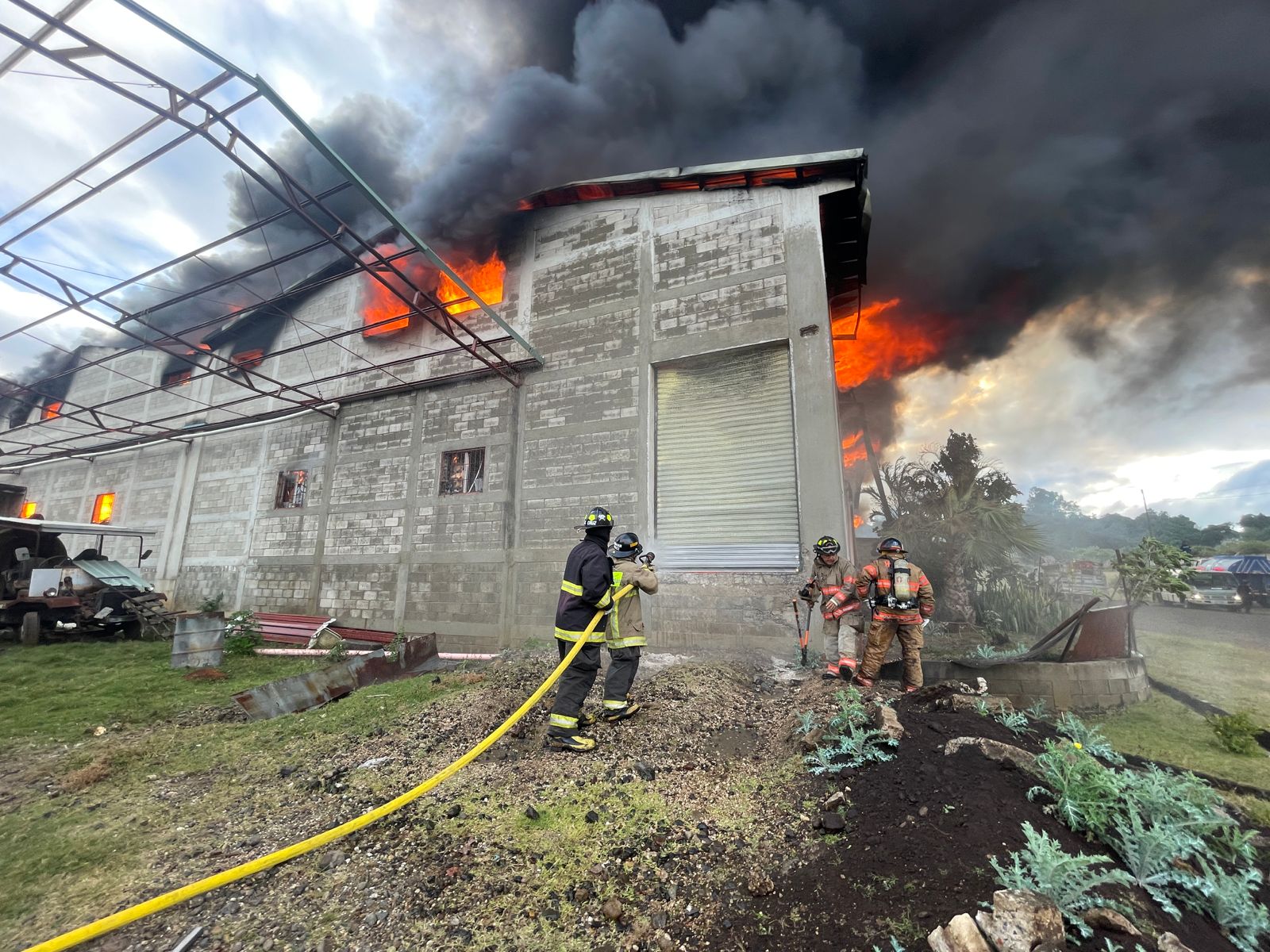 Socorristas combaten un incendio en una bodega en la antigua ruta a Amatitlán. (Foto Prensa Libre: Bomberos Voluntarios)