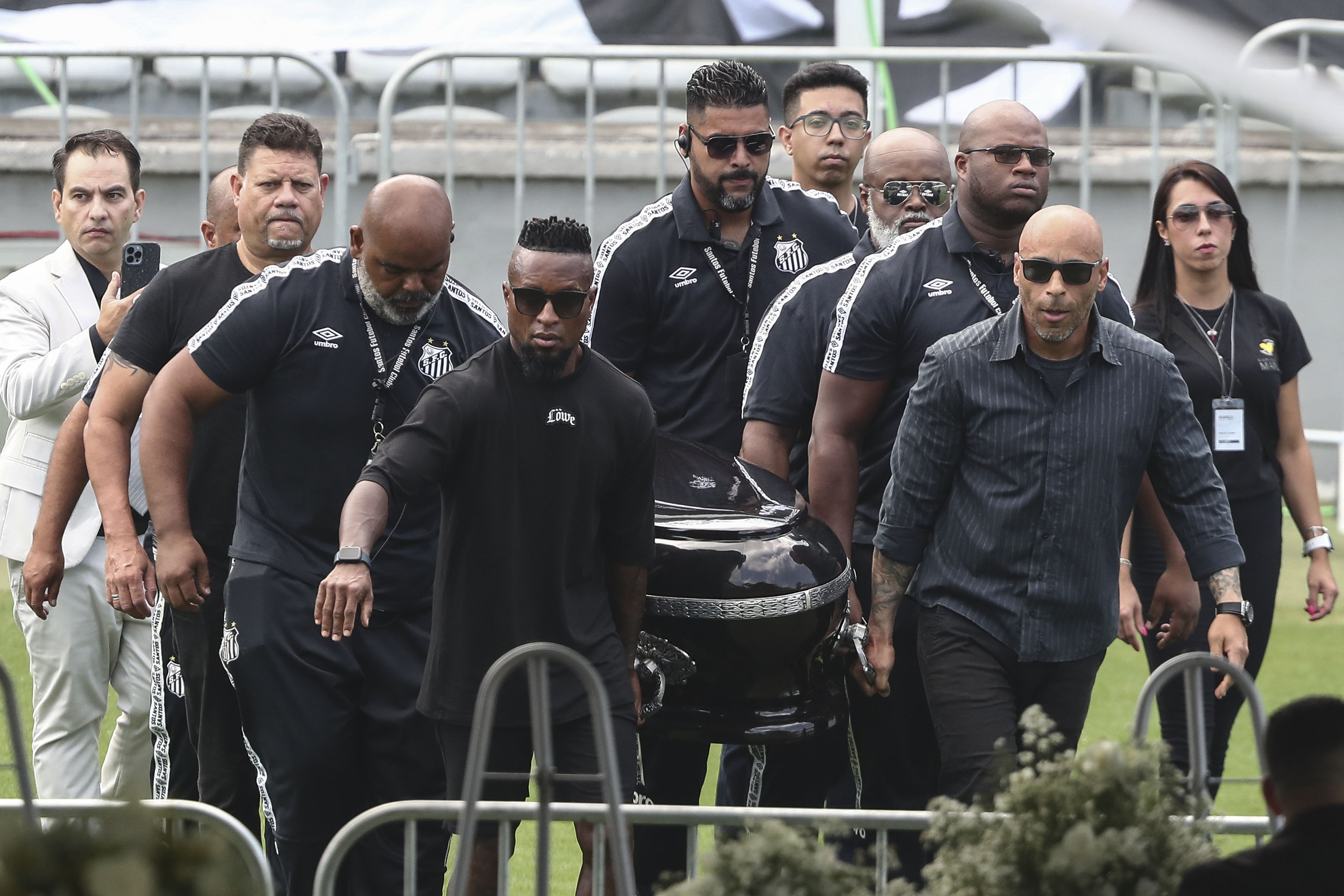 El hijo de Pelé Edinho (frente d), y el exfutbolista Zé Roberto (frente i) y amigos del Edson Arantes do Nascimento 'Pelé cargan el ataúd donde están los restos de Pelé que está siendo velado en el estadio del Santos. (Foto Prensa Libre: EFE)