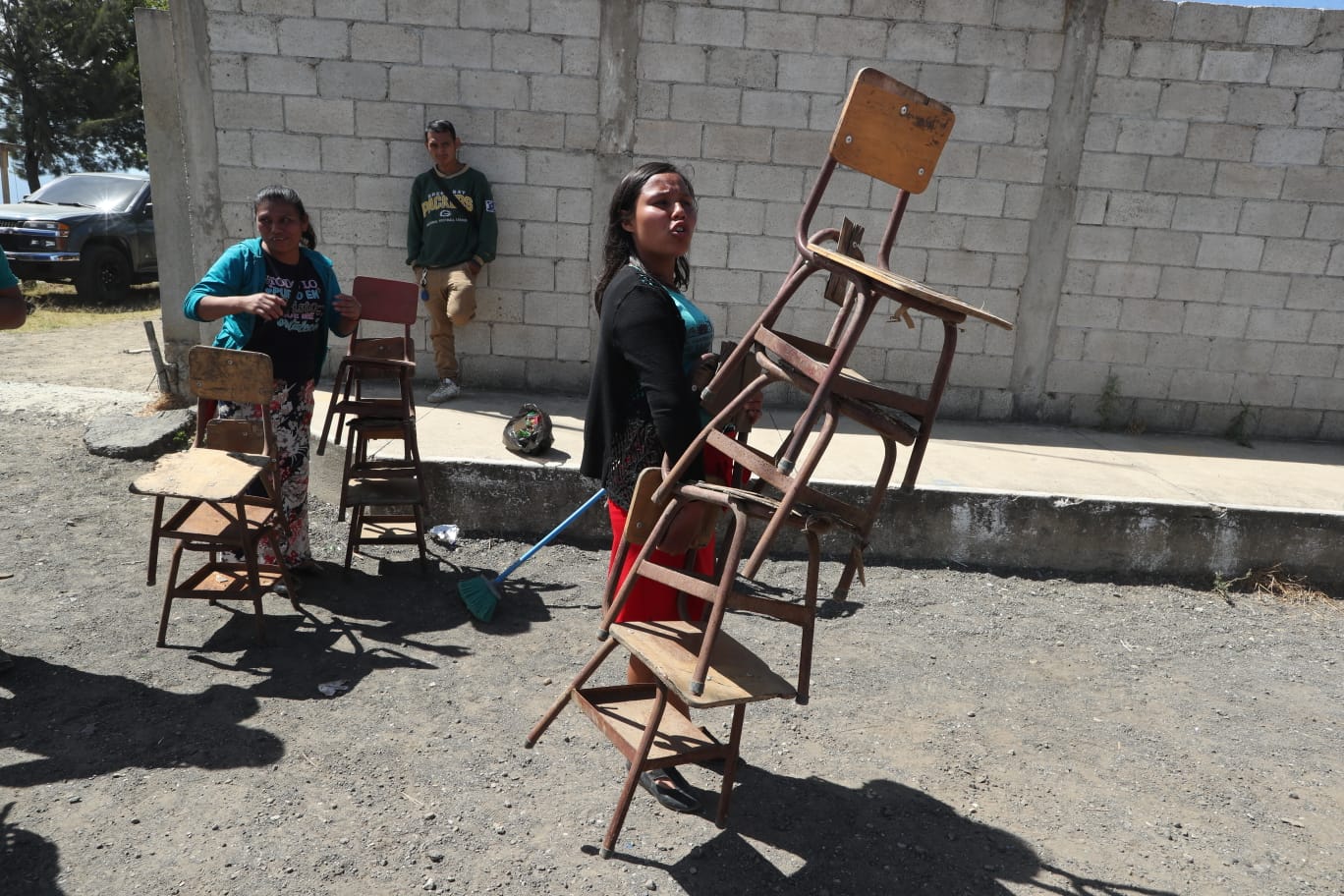 Durante el primer día de regreso a clases, los padres de familia buscaron entre escritorios desechados para repararlos y llevarlos al día siguiente para que sus hijos puedan finalmente recibir clases. (Foto Prensa Libre: María José Bonilla) 