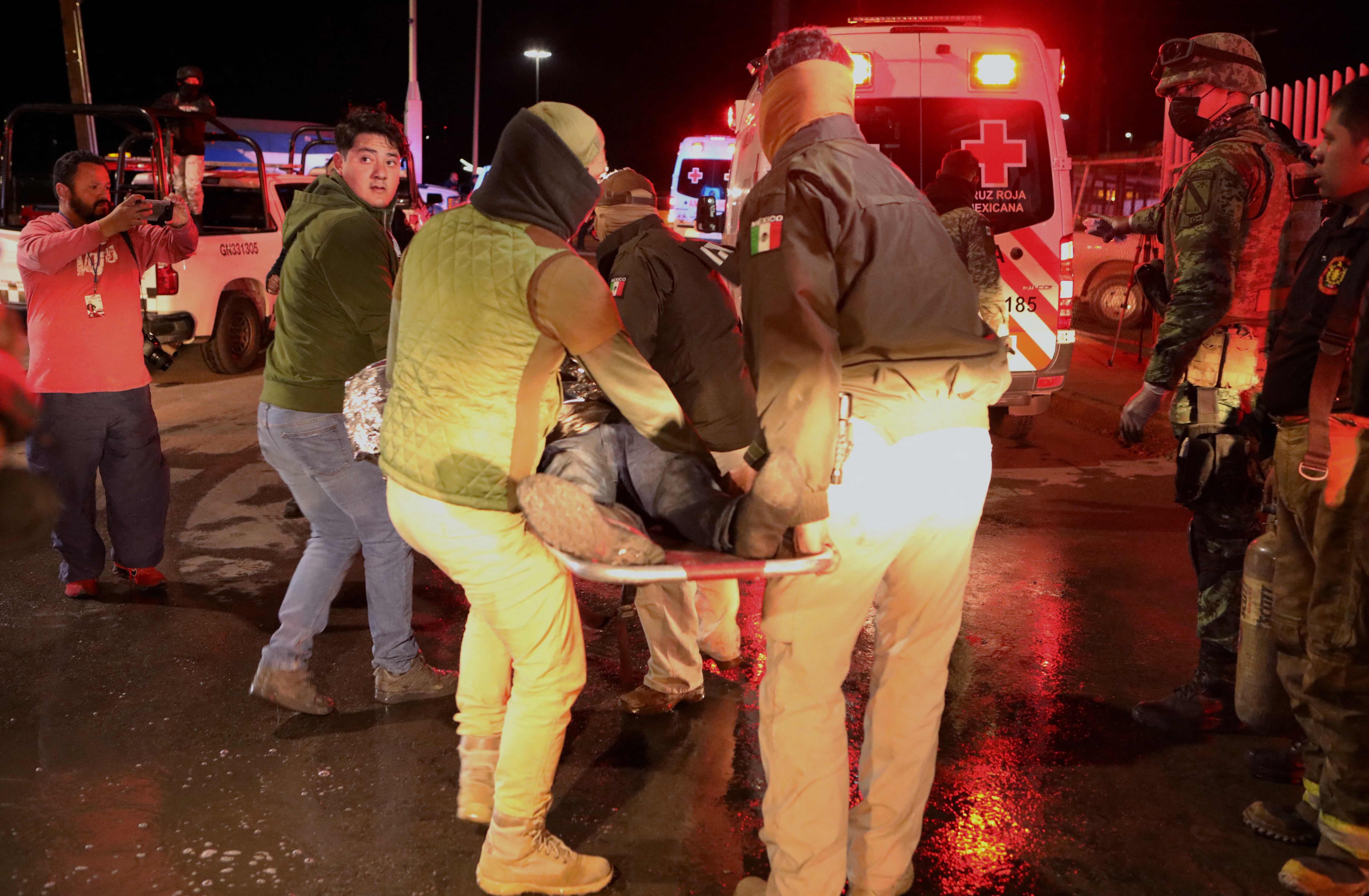 Policías trasladan a un migrante quemado en el incendio en un albergue para migrantes en Ciudad Juarez, México, que dejó 39 muertos. (Foto Prensa Libre: AFP)