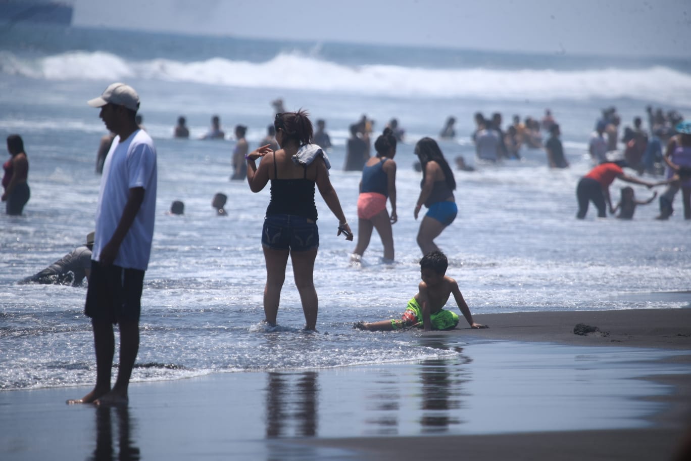 En la orilla del mar niños y adultos corrían para chocar con las olas del mar, mientras que otros únicamente disfrutaban el descanso.'