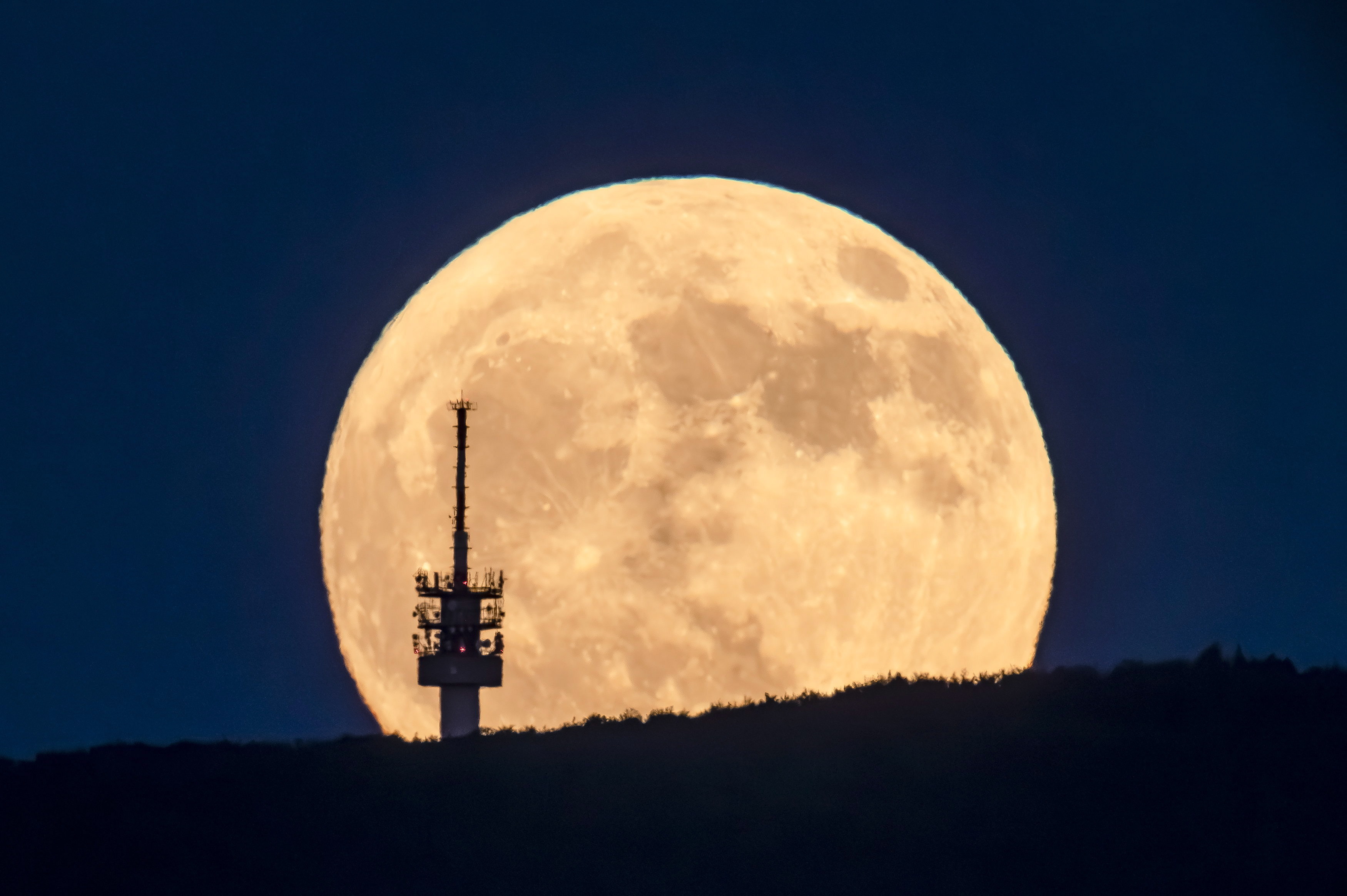 -FOTODELDIA- EA7400. MATRAVEREBELY, 04/06/2023.- La luna emerge tras una torre de telecomnicaciones vista desde Matraverebely en Hungría, este sábado noche. La conocida como luna de fresa coincide con el plenilunio de junio y adopta este nombre porque coincide con la cosecha de la fresa en el noroeste de Estados Unidos. EFE/ Peter Komka