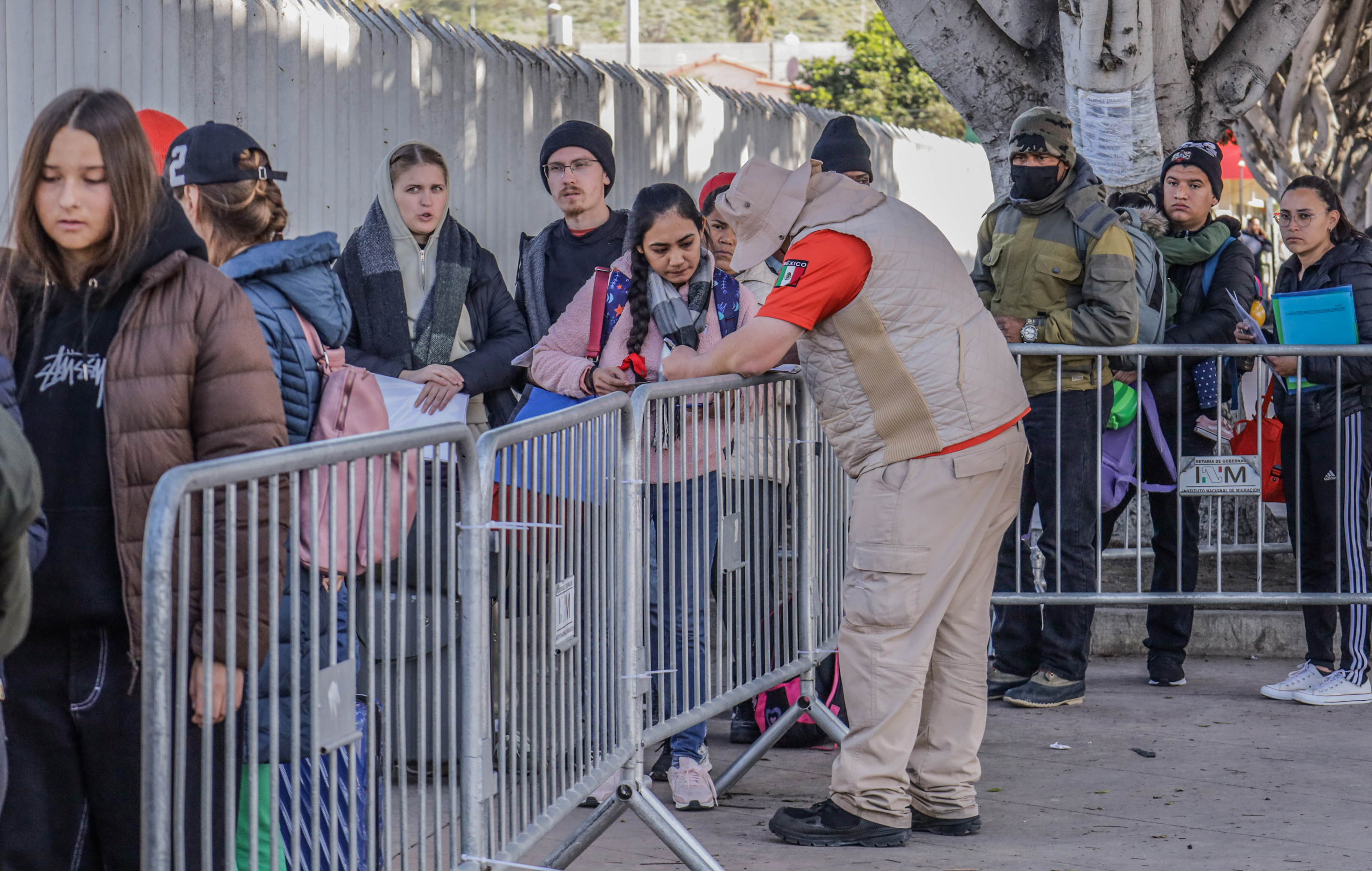 Integrantes del Instituto Nacional de Migración (INM) de México orientan a migrantes en el puerto fronterizo de San Ysidro, en la ciudad de Tijuana. tras anuncio del fin del Título 42. Foto Prensa Libre: EFE)