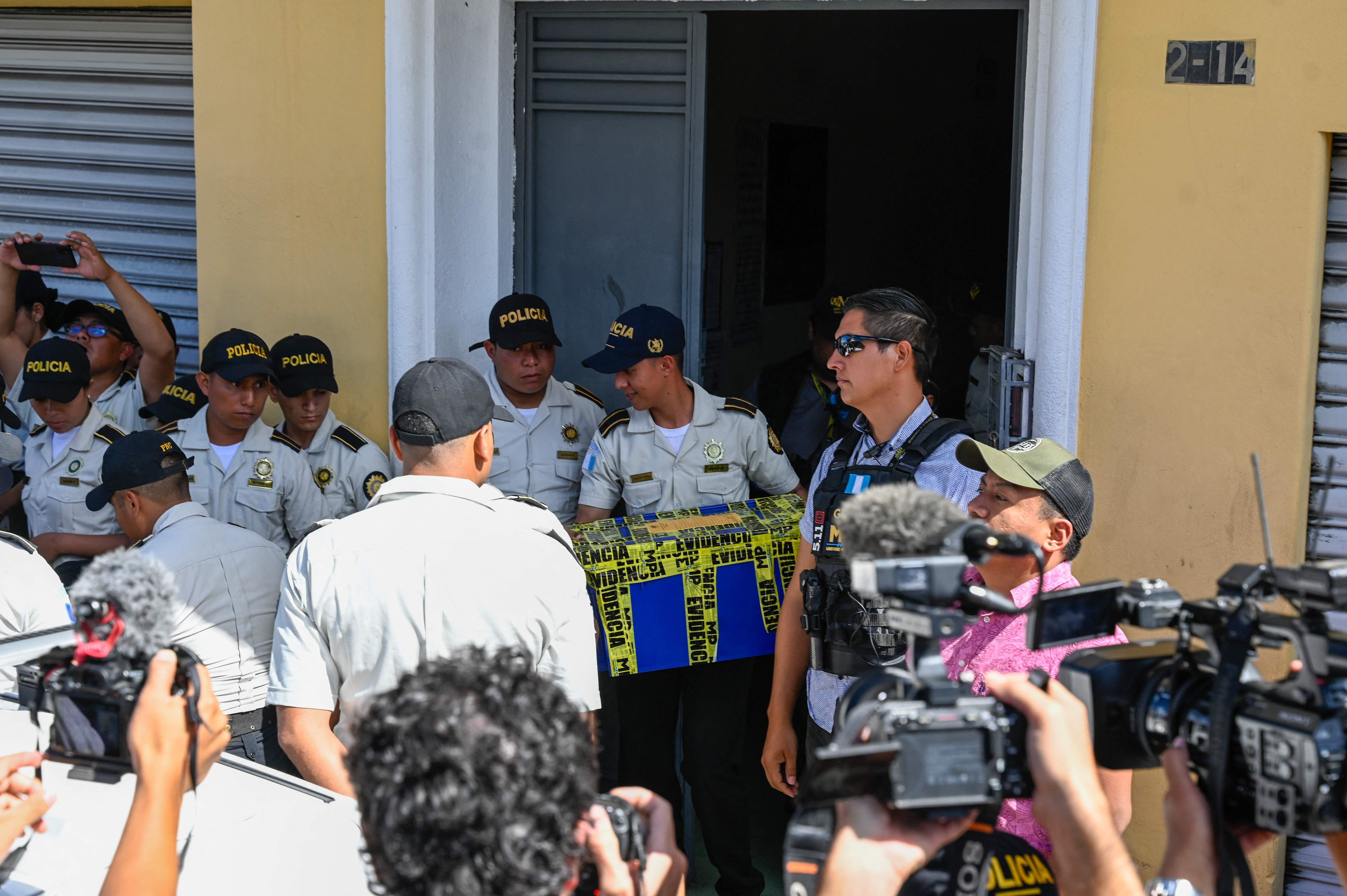 Agentes policiales salen con cajas de evidencia que secuestraron en un allanamiento practicado en la sede del partido Movimiento Semilla. Estas acciones han sido consideradas por el TSE y muchos sectores como intimidatorias. (Foto Prensa Libre: AFP)