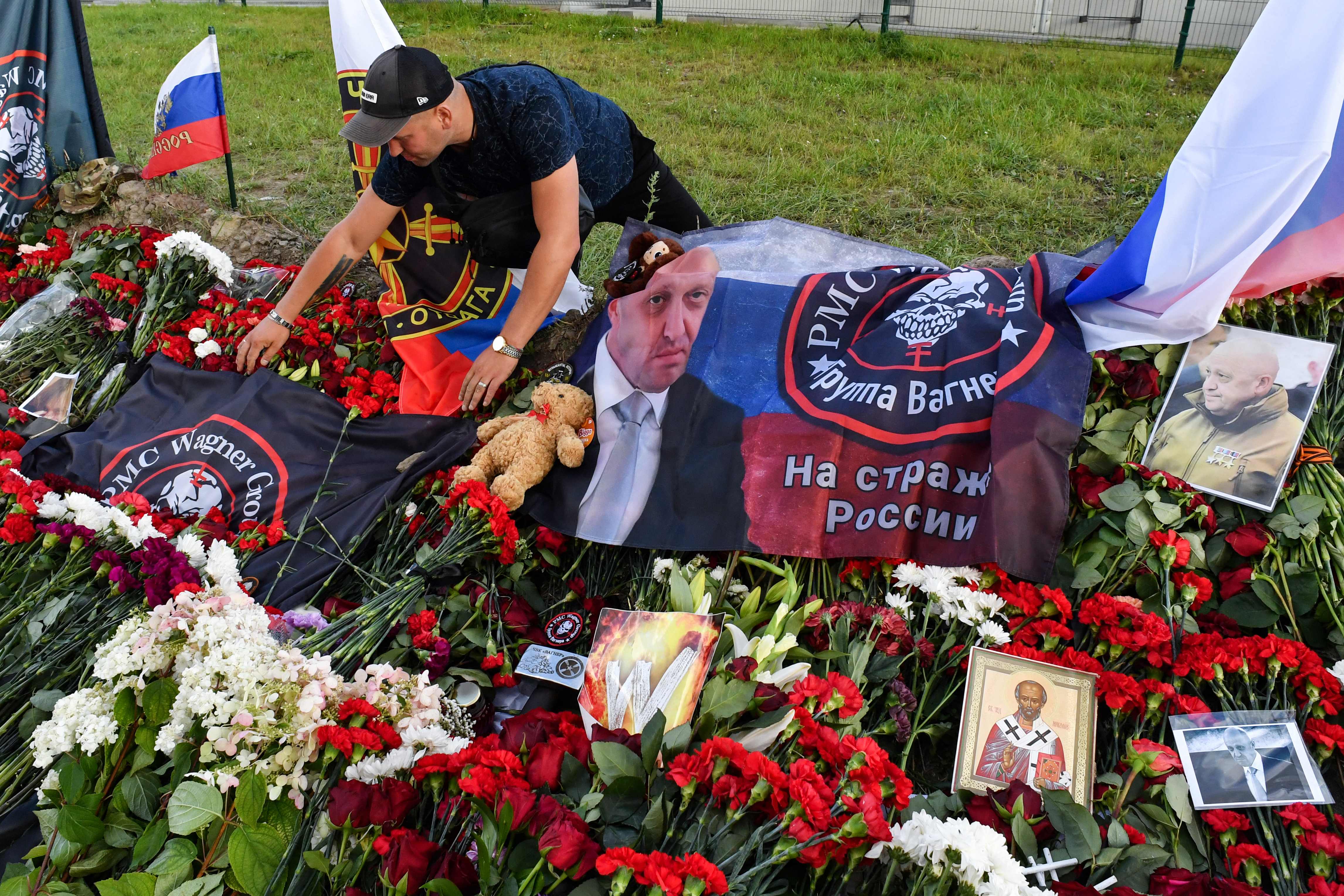 Un hombre coloca una bandera con el logotipo del grupo Wagner en un monumento improvisado a Yevgeny Prigozhin frente al Centro Wagner de la Compañía Militar Privada en San Petesburgo. (Foto Prensa Libre: AFP)