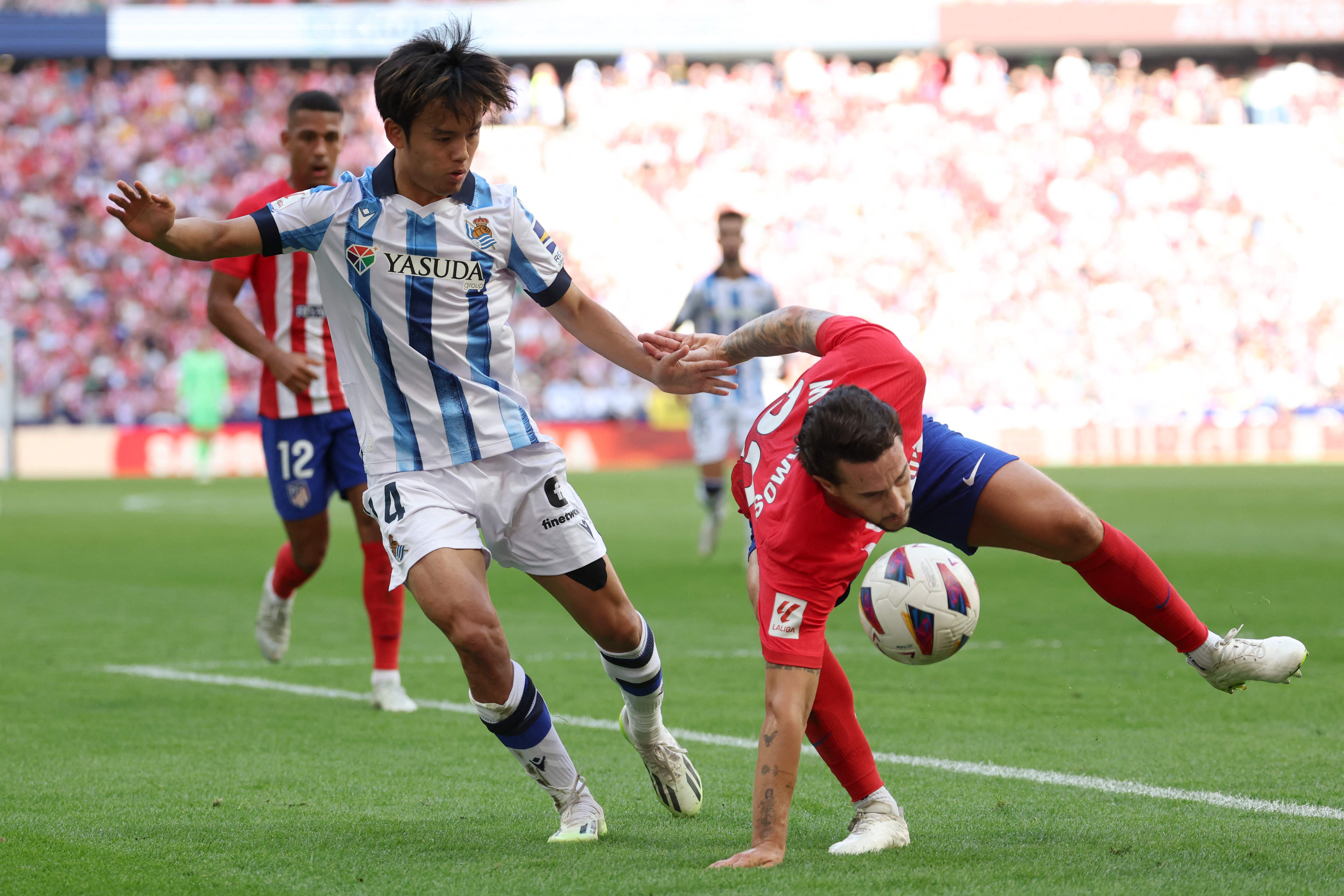 El jugador de la Real Sociedad, Takefusa Kubo, choca con el defensa del Atlético, Mario Hermoso.(Foto Prensa Libre: AFP)