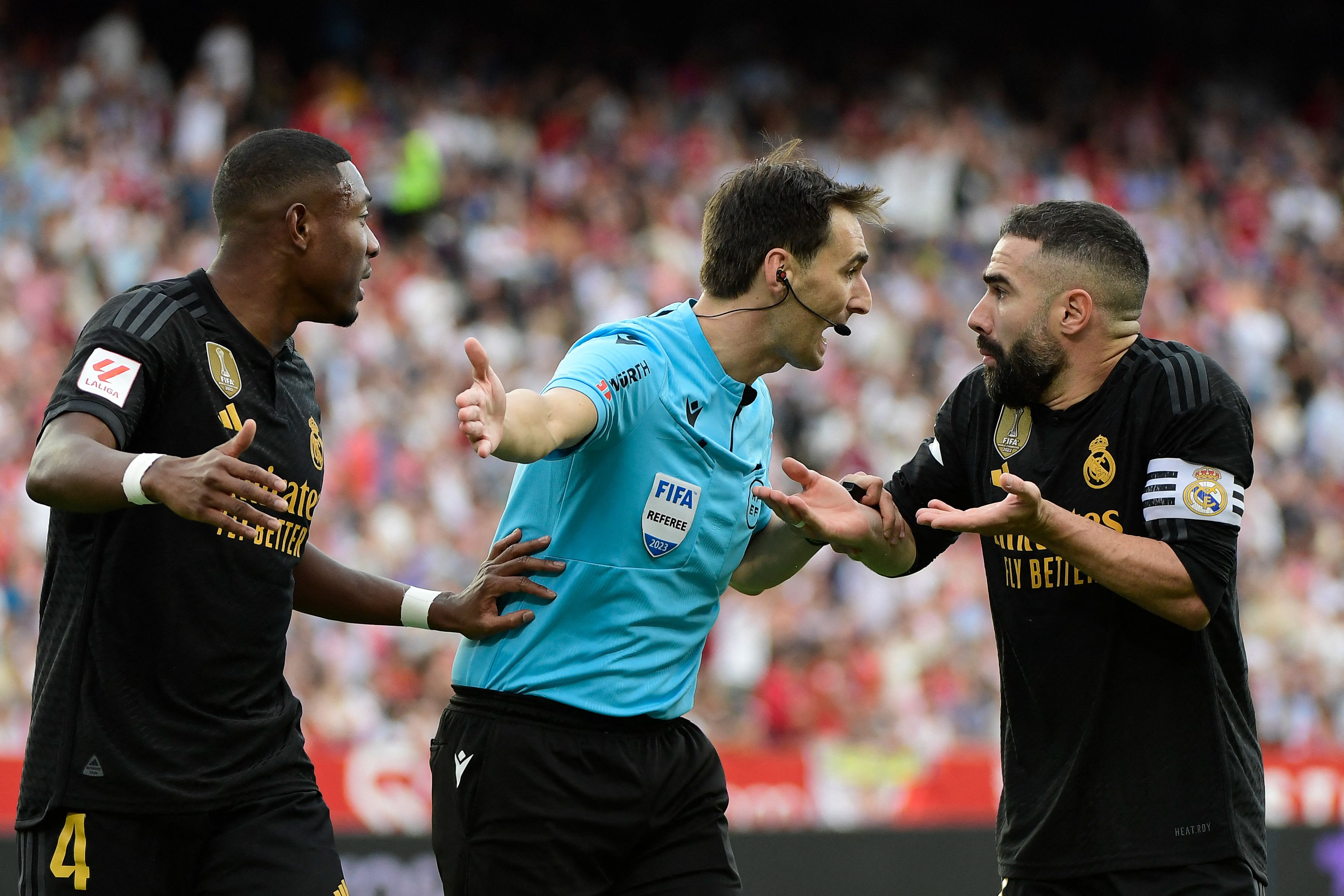 Los defensas del Real Madrid, David Alaba (i) y Dani Carvajal discuten con el árbitro Ricardo De Burgos Bengoetxea durante el partido ante el Sevilla. (Foto Prensa Libre: AFP)