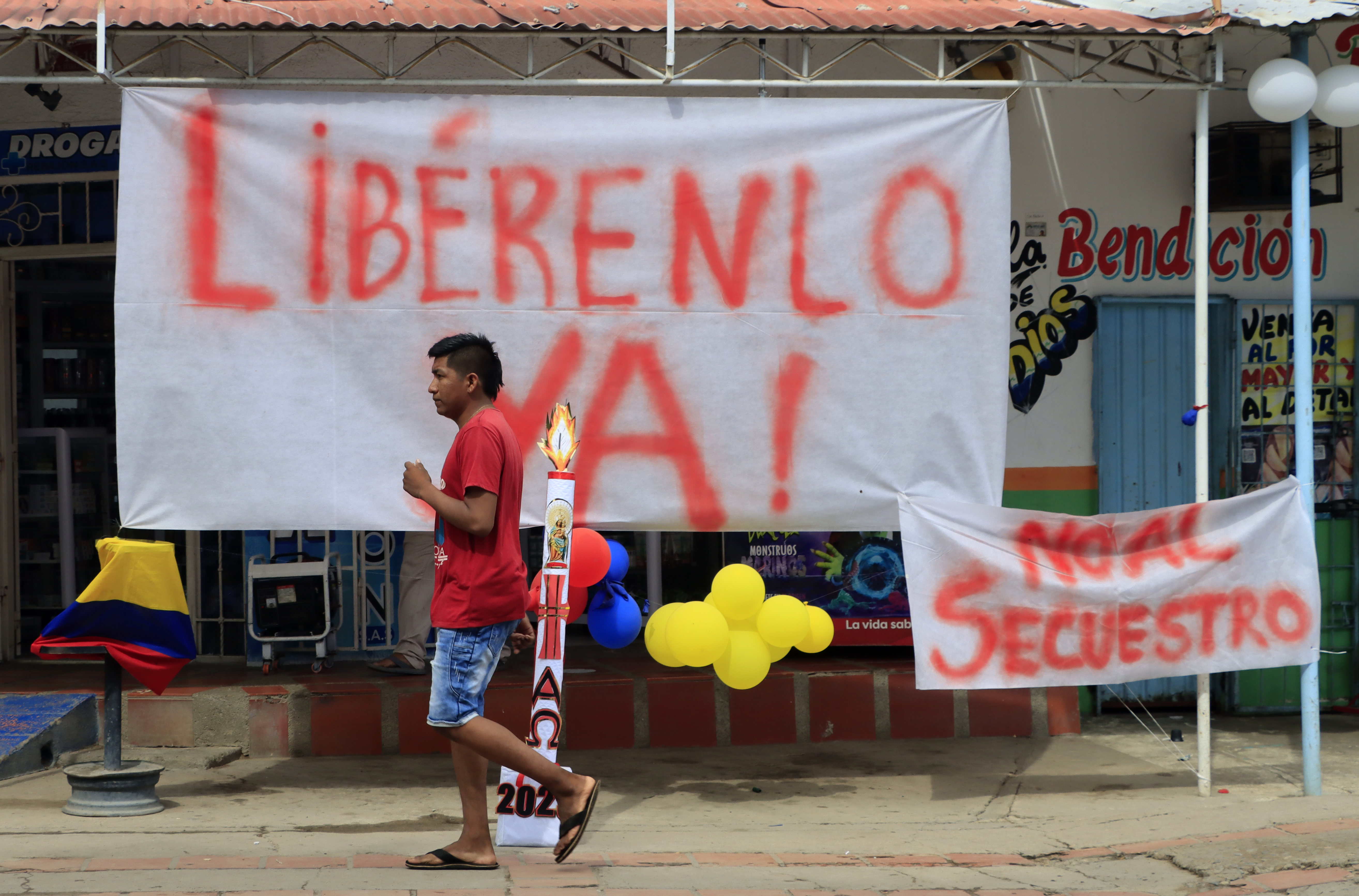 Un hombre camina hoy frente a carteles que piden la libertad y rechazan el secuestro de Luis Manuel Díaz, padre del delantero de la selección colombiana de fútbol y del club inglés Liverpool, Luis Díaz. (Foto Prensa Libre: EFE)