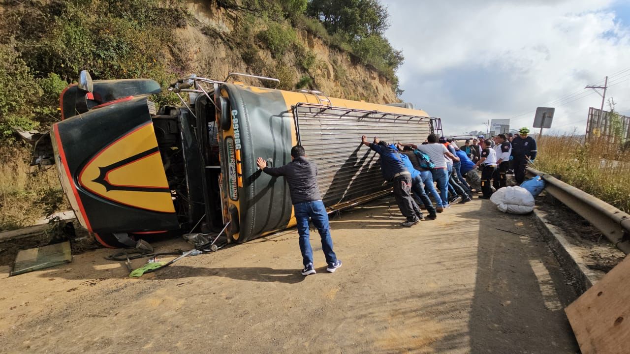 Personas intentar acomodar la unidad de transporte público luego del accidente. Fotografía: Cuerpos de socorro.