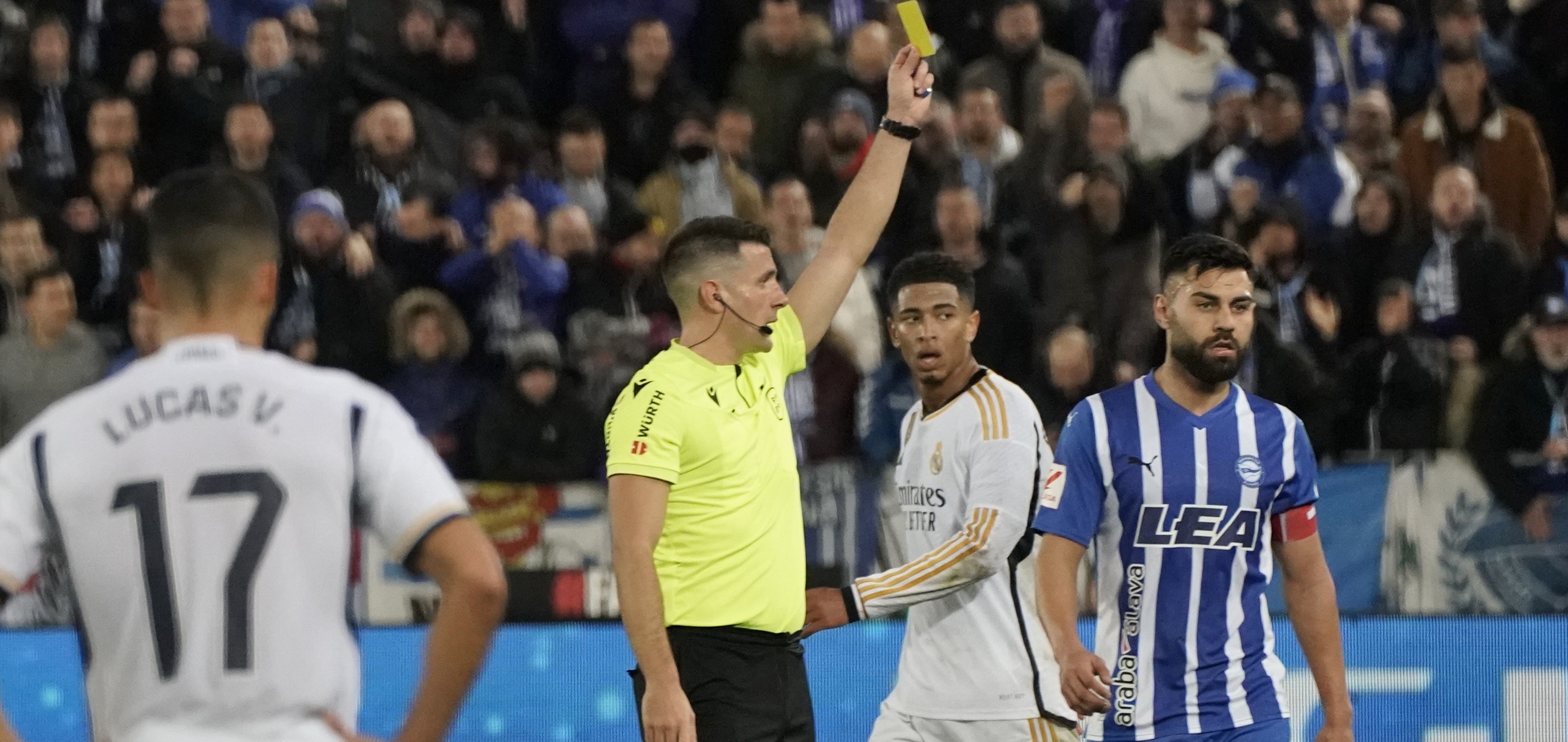 El colegiado Díaz de Mera Escuderos muestra tarjeta amarilla a Rubén Duarte (d), del Alavés, durante el encuentro de la jornada 18 de LaLiga entre el Deportivo Alavés y el Real Madrid. (Foto Prensa Libre: EFE)