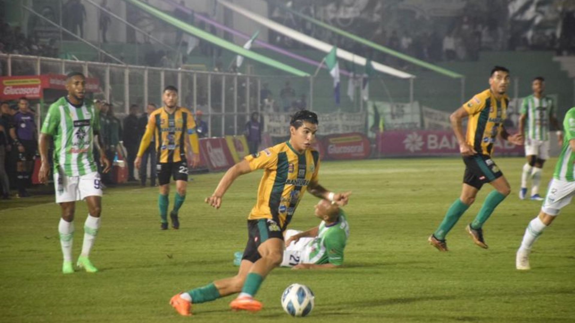 El jugador de Guastatoya, Jehú Fajardo, conduce el balón ante la mirada de su rival de Antigua, Romario Da Silva (99). (Foto Prensa Libre - Guastatoya Facebook)