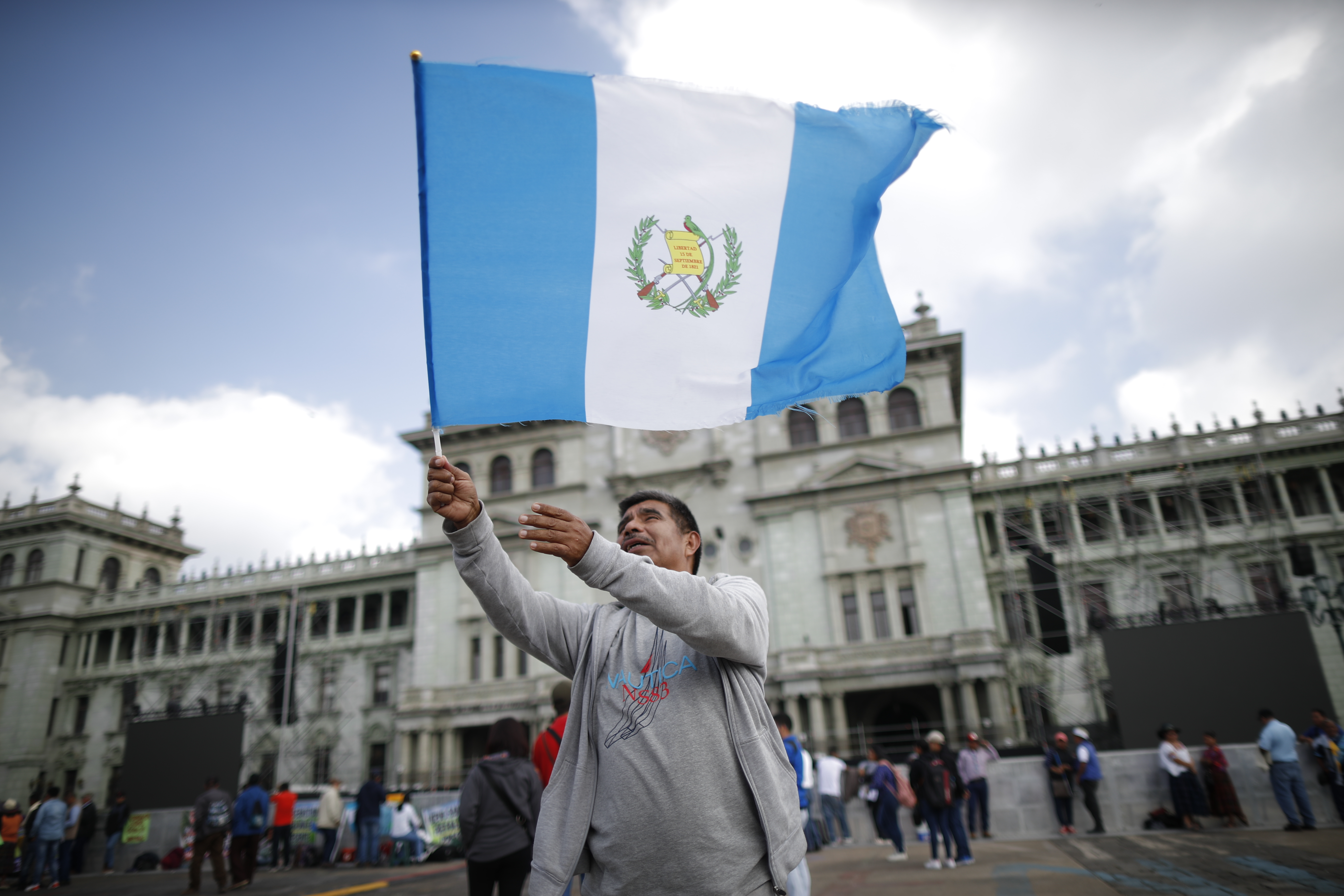 Persona ondea la bandera de Guatemala. Antes de entonar el Himno Nacional, muchas veces se realiza este acto.