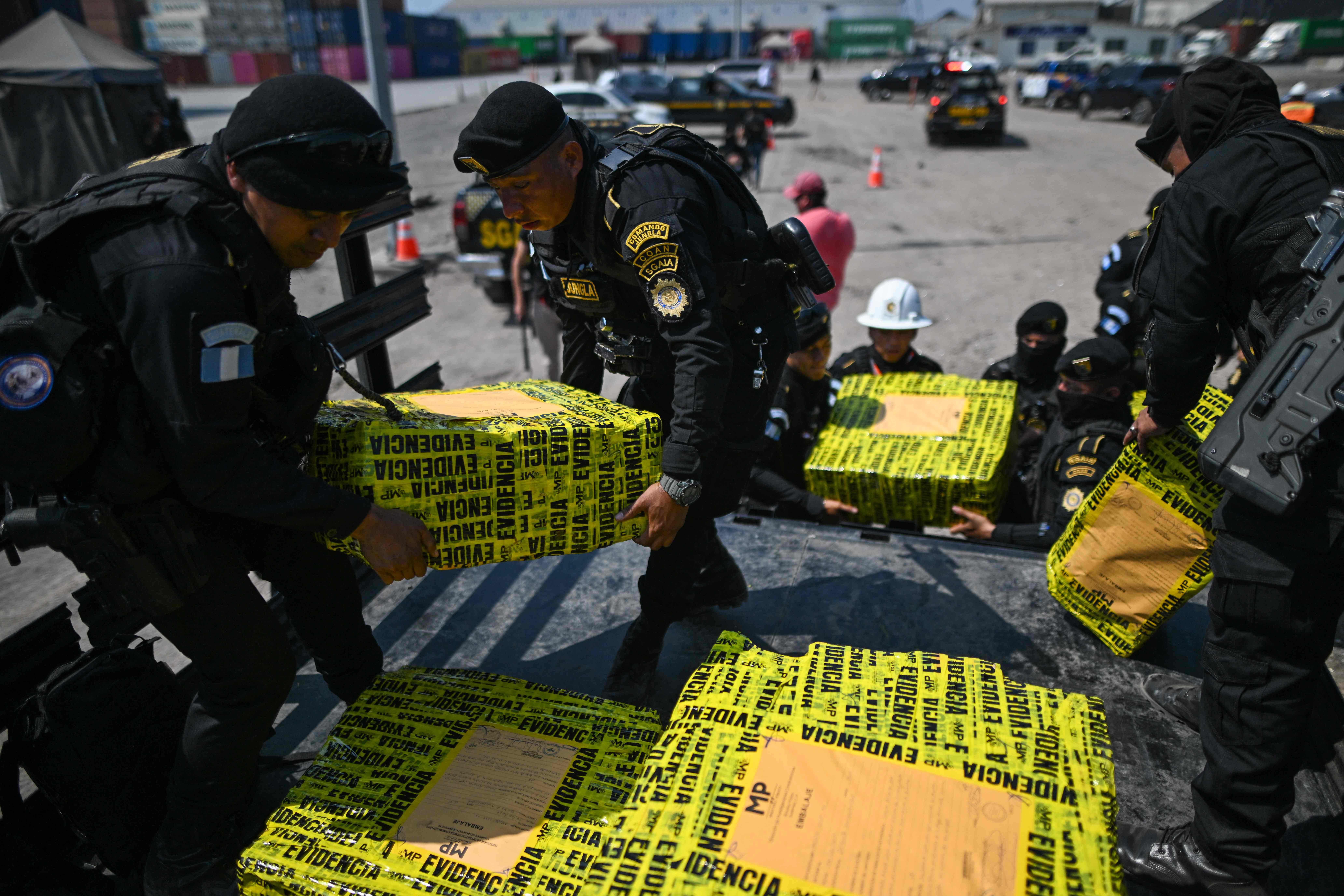 Police officers carry packages of seized cocaine found in a container in Puerto Quetzal, Escuintla, Guatemala on February 10, 2024. Guatemalan anti-narcotics authorities seized 525 kilos of cocaine hidden in a container that arrived at a port on the Pacific from Costa Rica, official sources said Saturday. (Photo by JOHAN ORDONEZ / AFP)