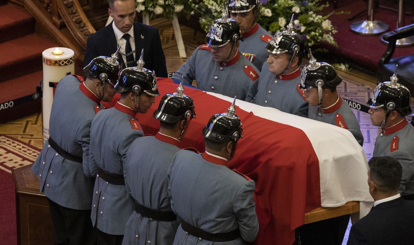 Agentes sostienen el ataúd con el cuerpo del expresidente de Chile Sebastián Piñera, en la antigua sede del Congreso en Santiago. (Foto Prensa Libre: EFE)