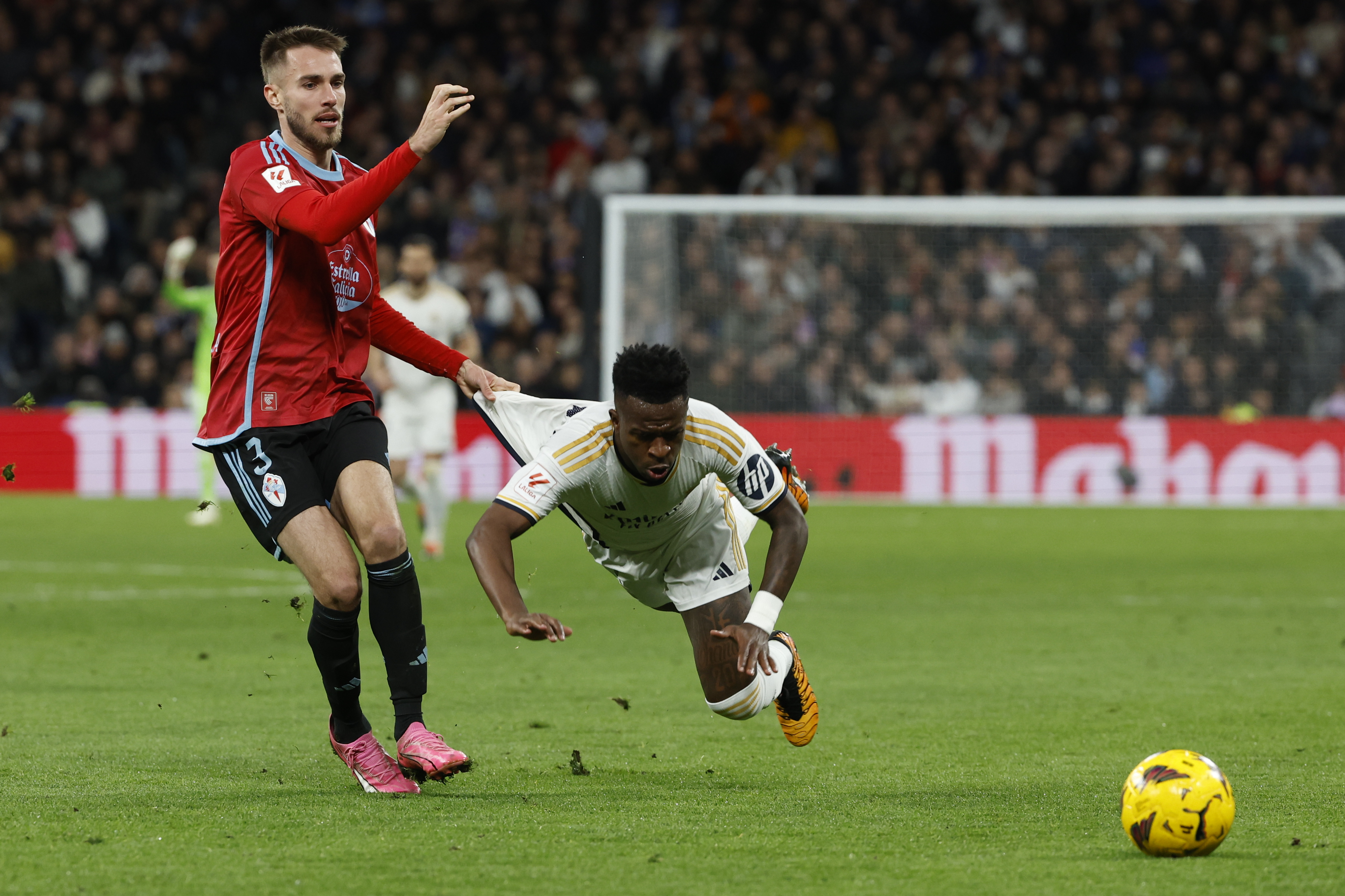 El delantero brasileño del Real Madrid, Vinicius Jr. (d), cae tras la entrada de Óscar Mingueza, del Celta. (Foto Prensa Libre: EFE)