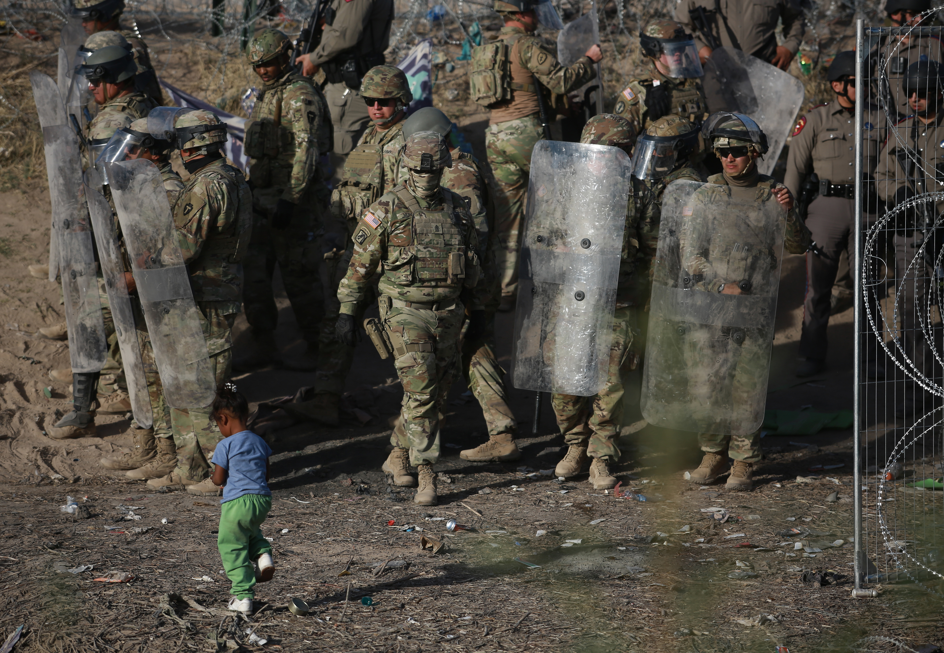 Una niña camina frente a integrantes de la Guardia Nacional de Texas, mientras vigilan este viernes la entrada de migrantes que permanecen en las inmediaciones del la frontera con Estados Unidos,en Ciudad Juárez, Chihuahua (México). . (Foto Prensa Libre: EFE).