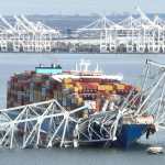 (FILES) In this aerial image, the steel frame of the Francis Scott Key Bridge sits on top of a container ship after the bridge collapsed, Baltimore, Maryland, on March 26, 2024. The US Federal Bureau of Investigation (FBI) has launched a criminal probe targeting the container ship that crashed into a major road bridge in Baltimore last month, collapsing it and killing six people, US media reported on April 15, 2024. (Photo by Jim WATSON / AFP)