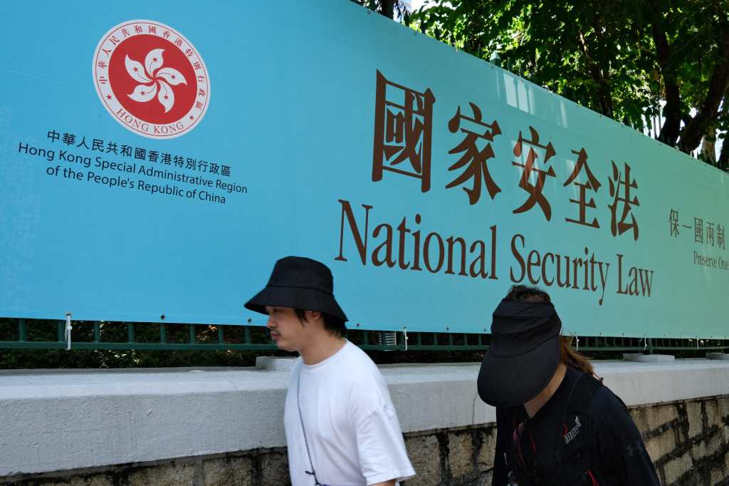 (FILES) People walk past a banner for the National Security Law in Hong Kong on July 15, 2020. A Hong Kong court will deliver verdicts this week in the biggest case brought against pro-democracy campaigners since China imposed a national security law to crush dissent. Forty-seven people from a cross-section of Hong Kong's then-opposition face life in prison on subversion charges for political activities in 2020, following democracy protests that saw millions take to the streets. (Photo by Anthony WALLACE / AFP) / To go with Hong Kong-China-politics-law-democracy-trial, ADVANCER