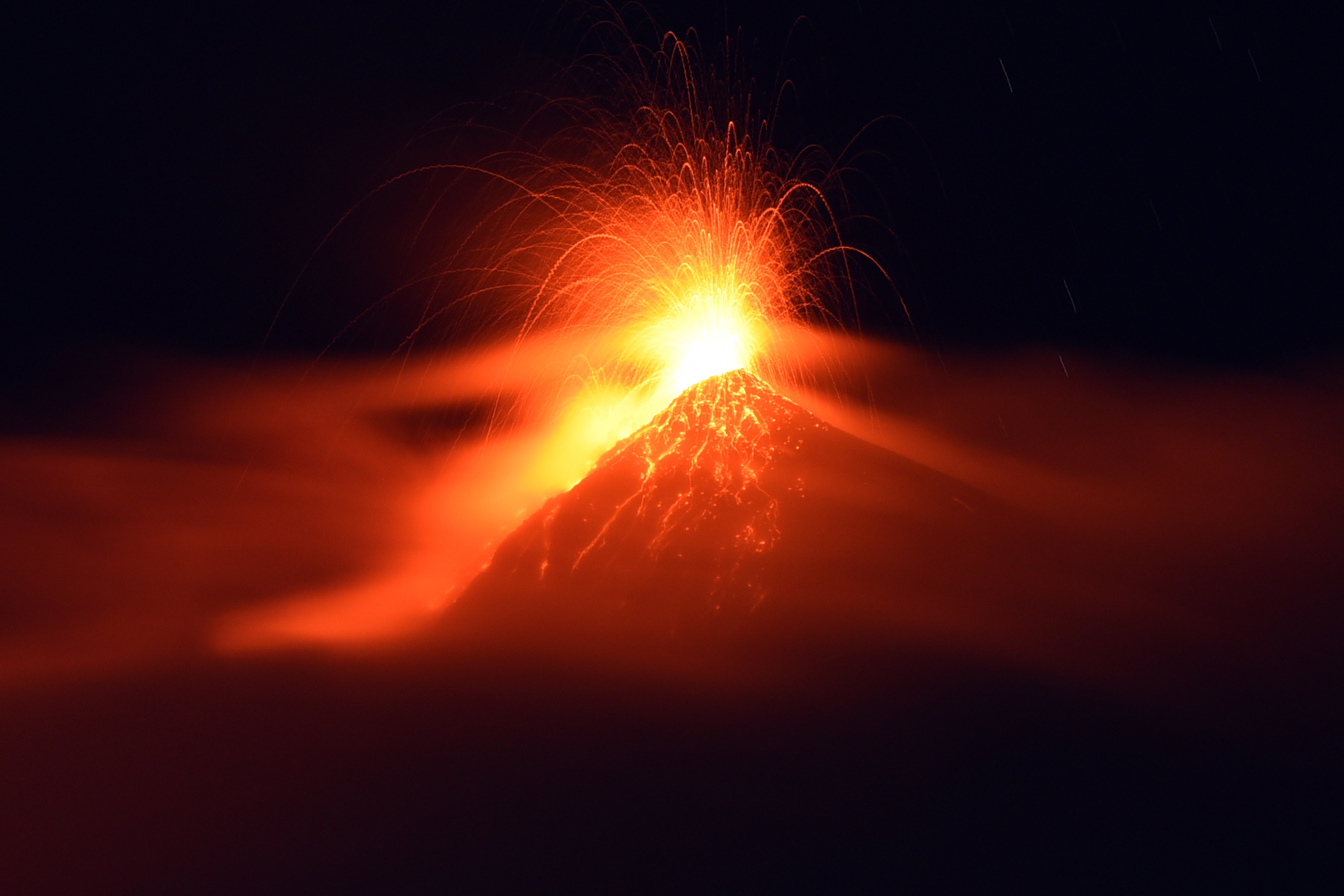 The Fuego volcano, seen from San Juan Alotenango municipality, Sacatepequez departament, about 65 km southwest of Guatemala City, erupts on November 10, 2015. Emergency service officials in Guatemala on Tuesday issued an orange alert over increasing eruptions from the country's southeastern Fuego volcano and ordered the evacuation of a nearby hotel. The 3,763-meter (12,346-foot) high colossus -- whose name means "fire" in Spanish -- showed heightened activity overnight, sending columns of ash high into the sky, spilling lava down its side and provoking small tremors.  AFP PHOTO / JOHAN ORDONEZ