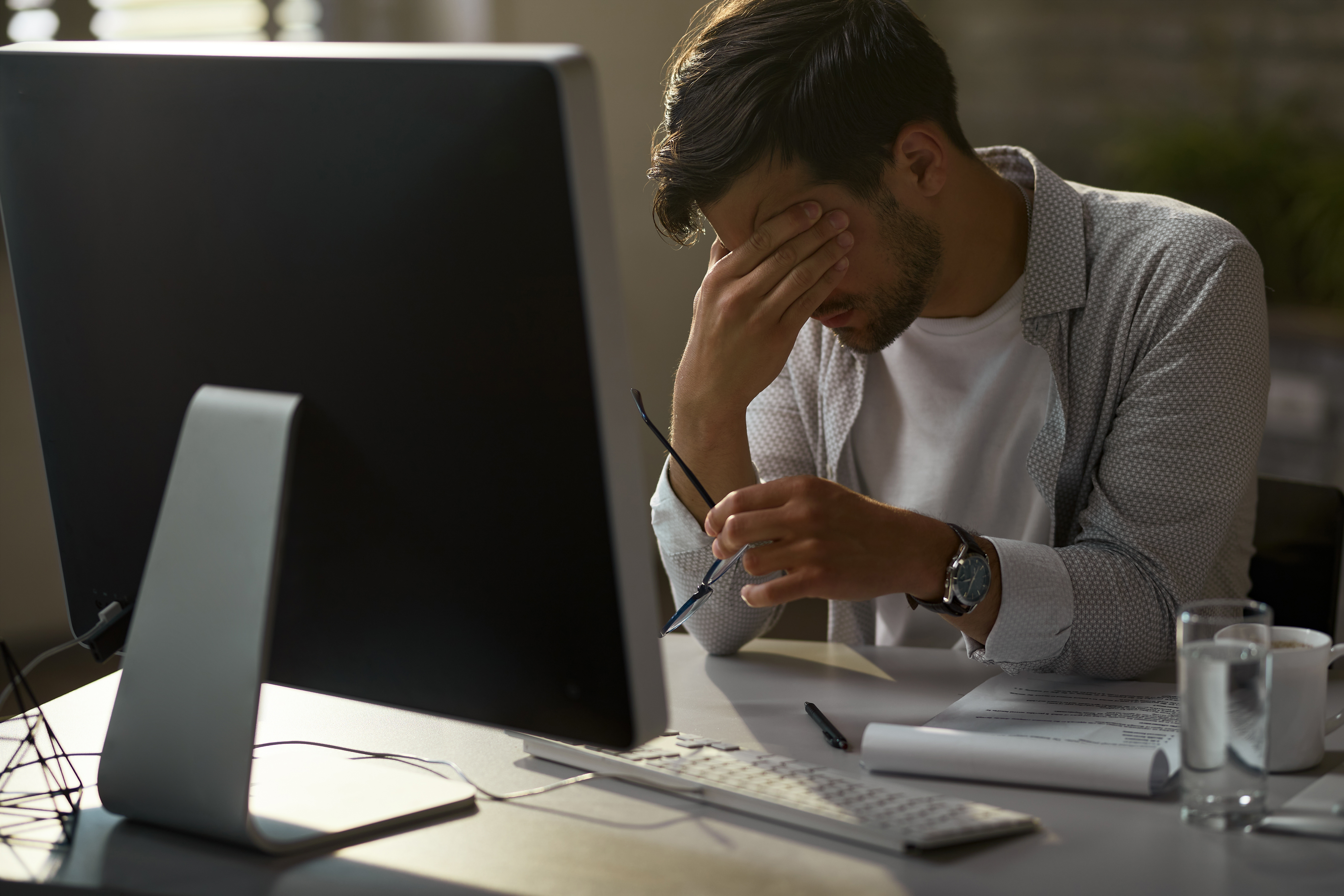 Tired businessman having a headache while working on a computer in the office.