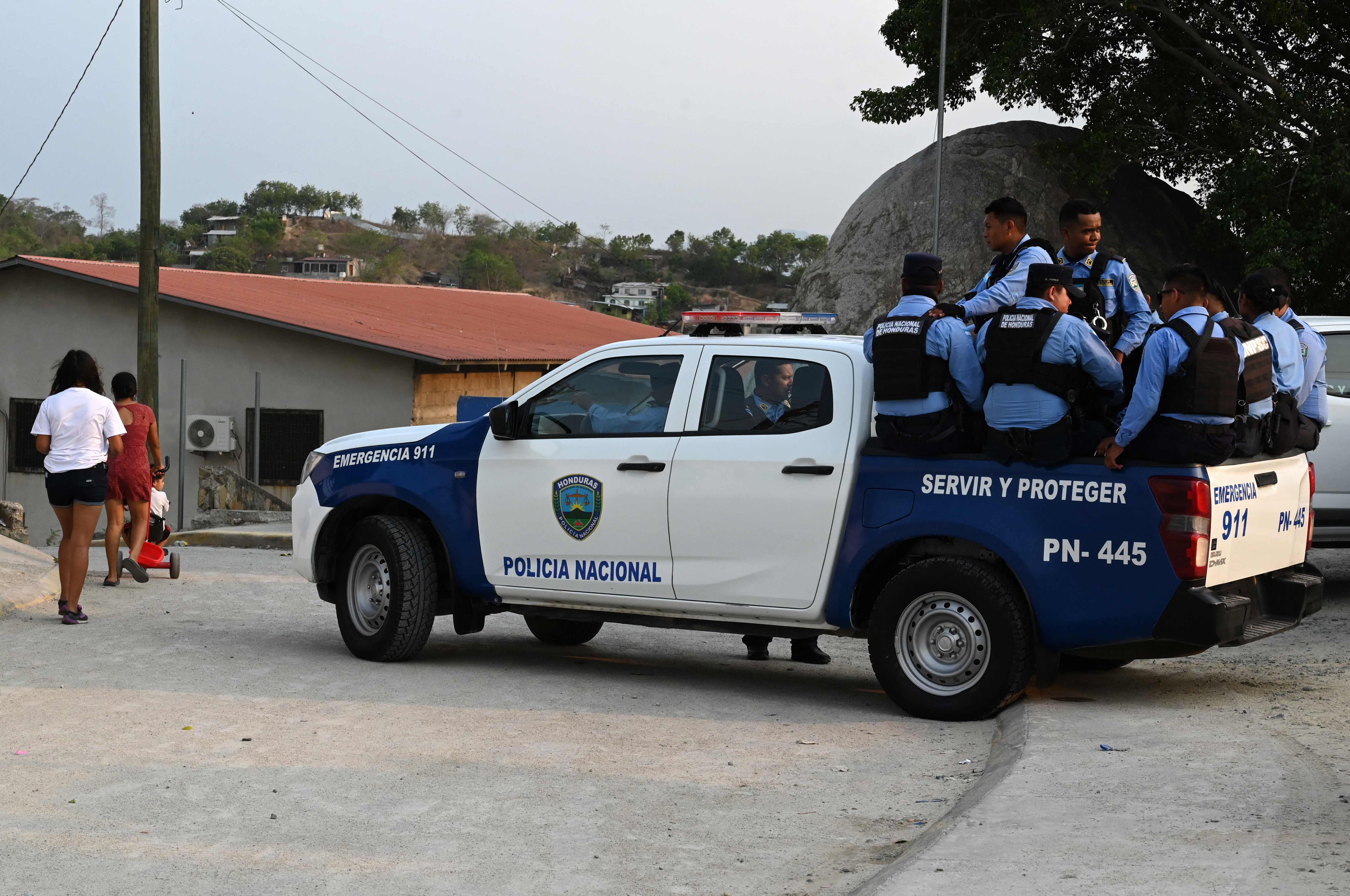 Honduran National Police members patrol during security operations in Lomas del Carmen, where the authorities and the Centre for Legal Medicine and Forensic Sciences search for the remains of at least 40 neighbours allegedly executed by the criminal gang Los Aguacates, in the city of San Pedro Sula, 180 km north of Tegucigalpa, on May 29, 2024. Honduran authorities exhumed ten skeletons from clandestine graves in the north of the country, which they suspect are those of people killed by the feared gang members. In 2023, Honduras recorded a rate of 34 homicides per 100,000 inhabitants, almost six times the world average, due to the actions of gangs and drug traffickers. (Photo by Orlando SIERRA / AFP)
