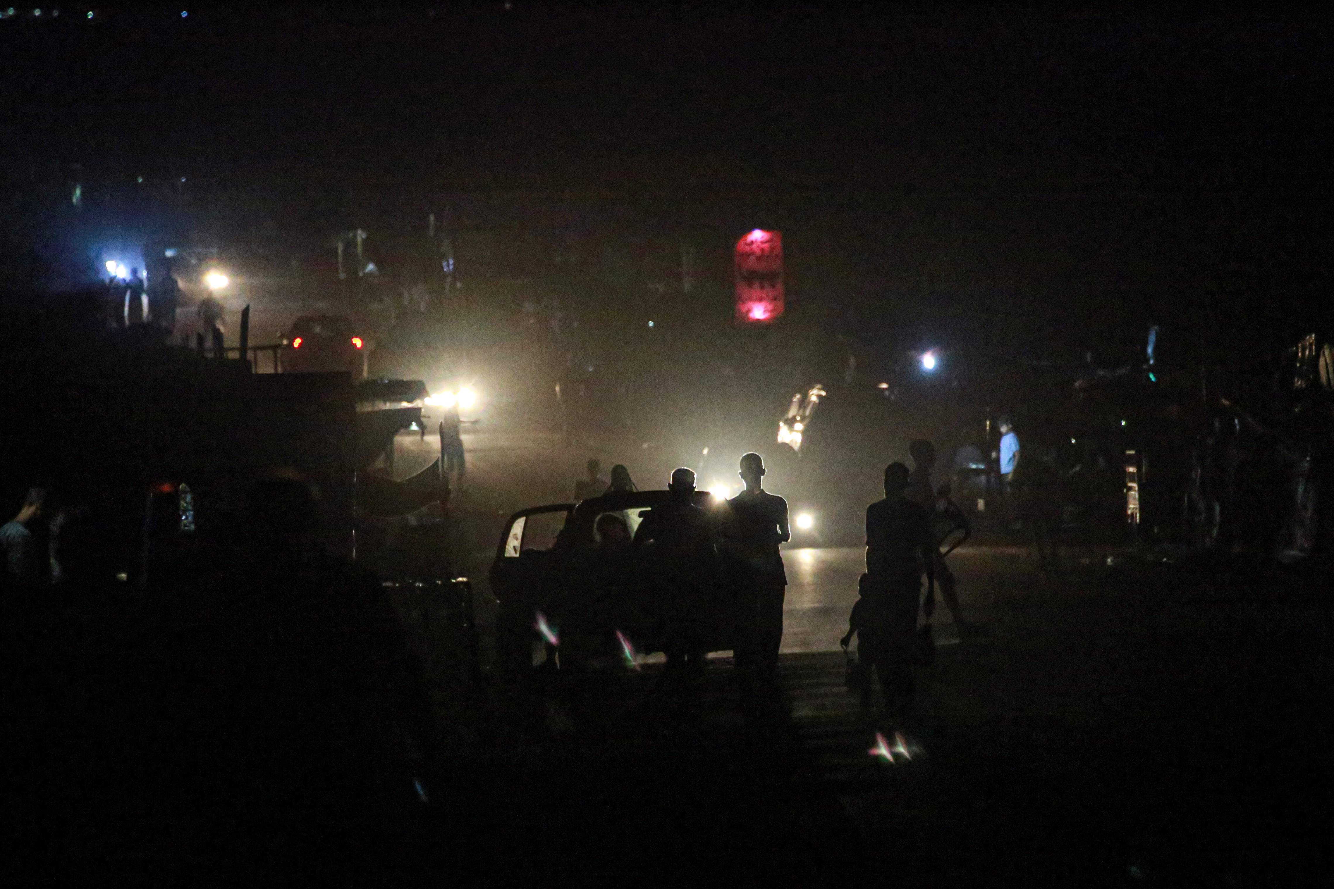 Palestinian walk along a street with no street lights due to the Israeli bombardment that has left most of the infrastructure of the Gaza Strip destroyed, in the central Gaza Strip town of al-Zawaida on June 25, 2024, amid the ongoing conflict between Israel and the Palestinian militant group Hamas. (Photo by Bashar TALEB / AFP)