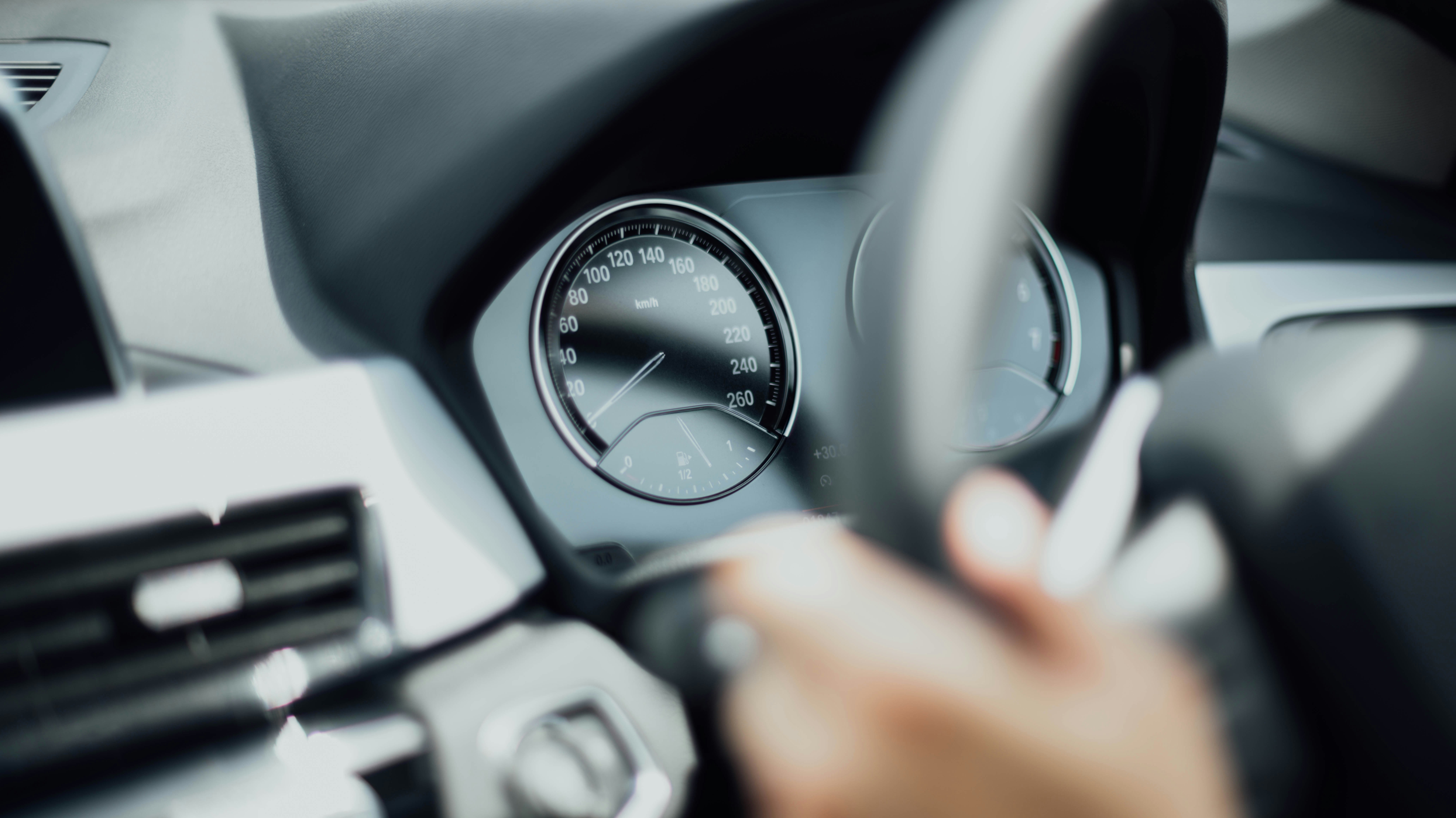 volante de un automóvil y se visualiza parte de una mano sobre el volante