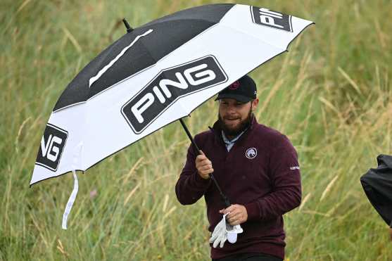 England's Tyrrell Hatton shelters from the rain under an umbrella as he leaves the 1st tee on the opening day of the 152nd British Open Golf Championship at Royal Troon on the south west coast of Scotland on July 18, 2024. (Photo by Paul ELLIS / AFP) / RESTRICTED TO EDITORIAL USE