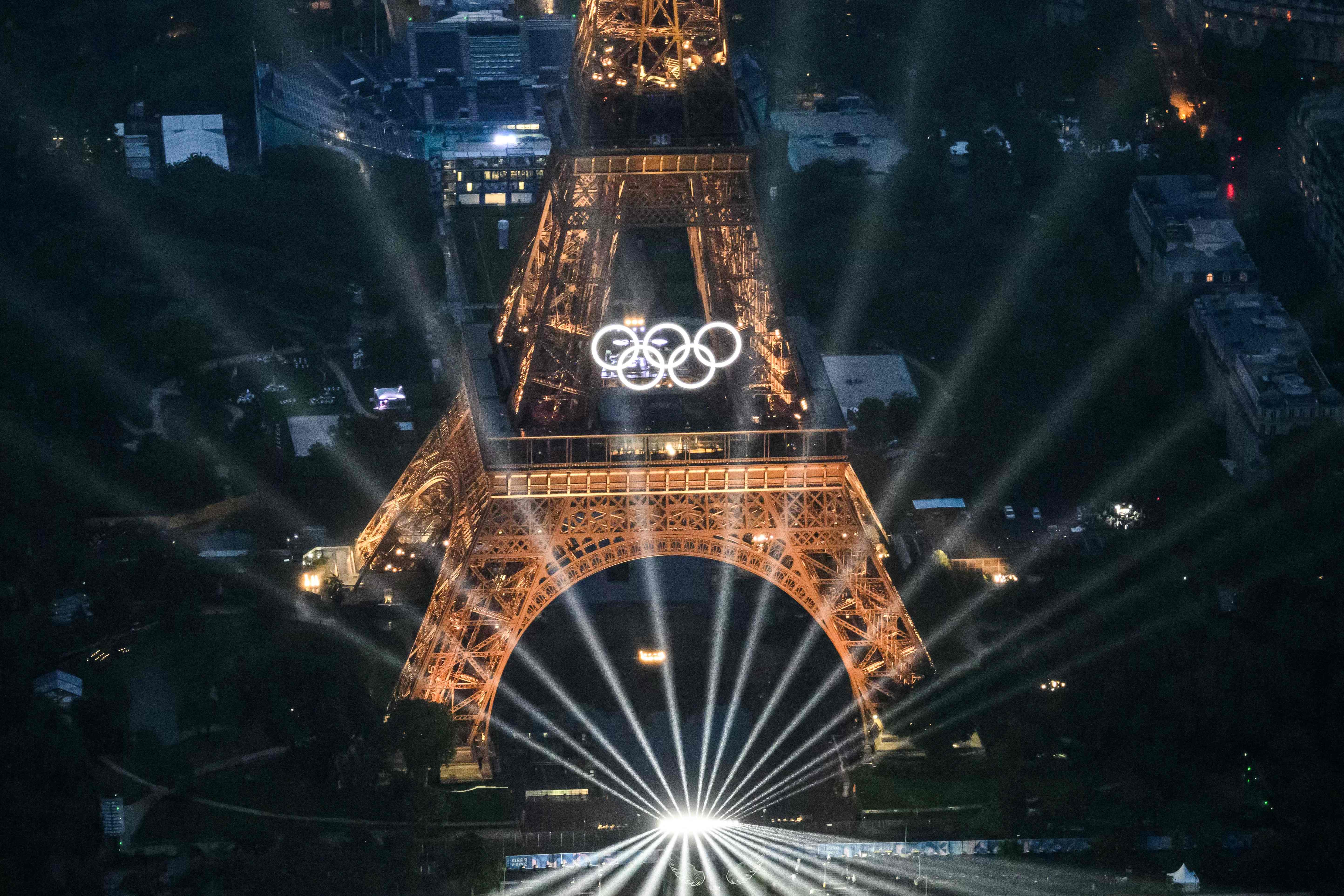 A photograph taken from an helicopter on July 26, 2024 shows an aerial view of the Eiffel Tower and the Olympics Rings lightened up during the opening ceremony of the Paris 2024 Olympic Games in Paris. (Photo by Lionel BONAVENTURE / POOL / AFP)