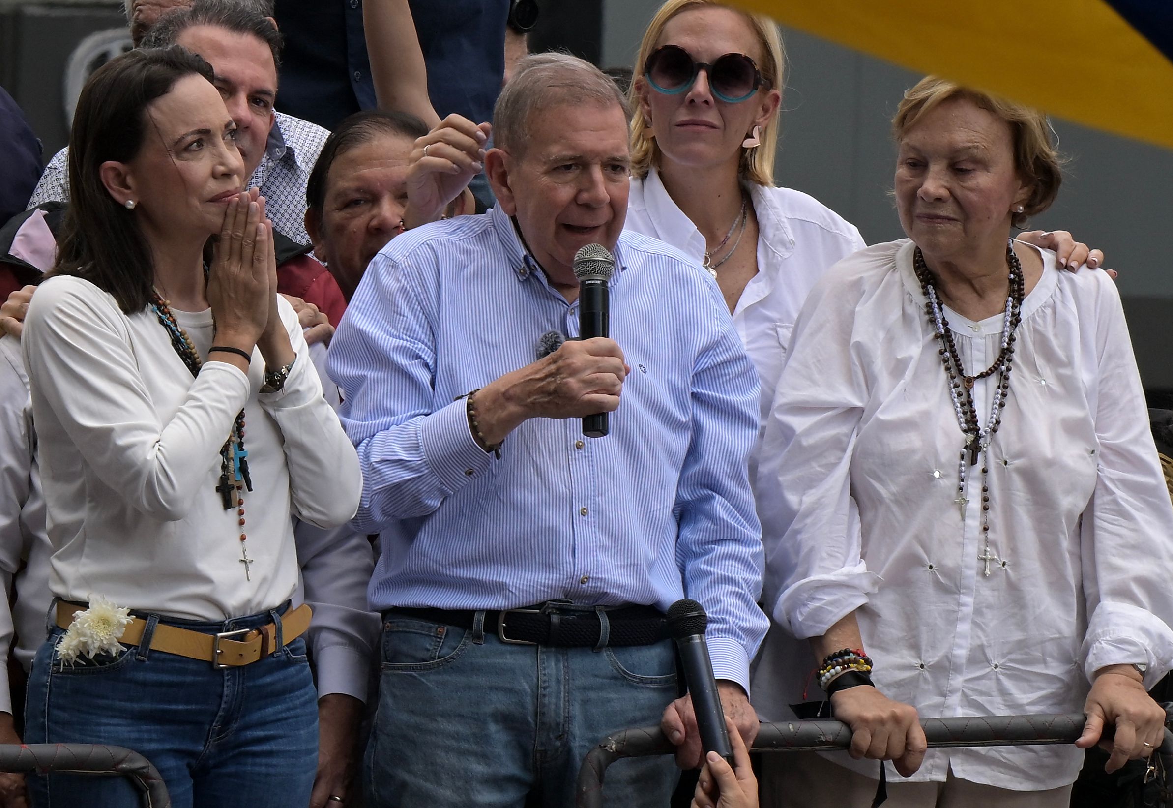 El candidato presidencial de la oposición venezolana Edmundo González Urrutia habla con sus partidarios mientras la líder de la oposición venezolana María Corina Machado (izq.), su esposa Mercedes López (der.) y su hija Mariana González (segunda der.) escuchan durante un mitin frente a la sede de las Naciones Unidas en Caracas el 30 de julio de 2024. (Foto Prensa Libre: AFP)