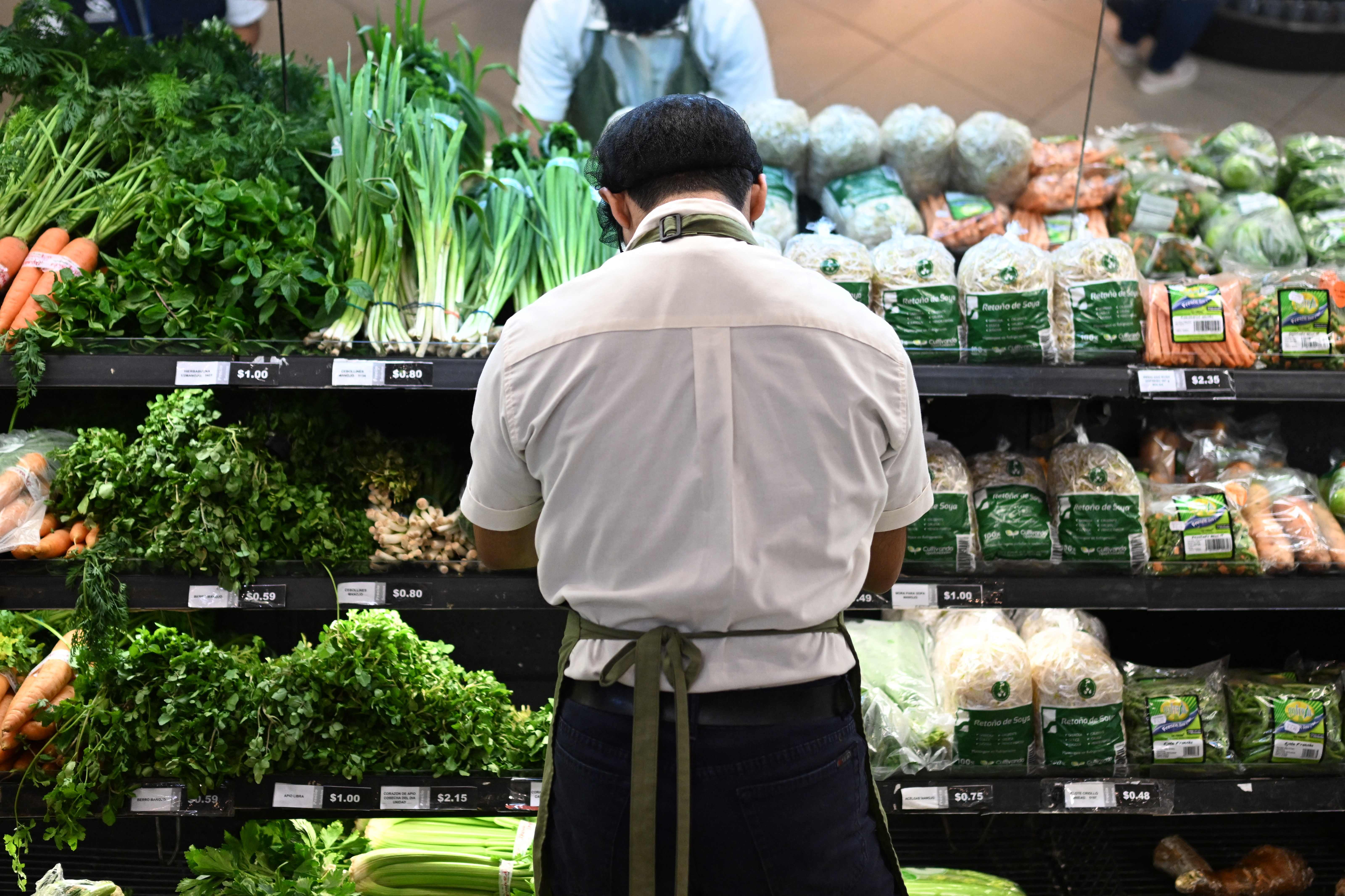 Un trabajador ordena frutas y verduras en un supermercado privado de San Salvador el 8 de julio de 2024. (Foto Prensa Libre: Marvin RECINOS / AFP)