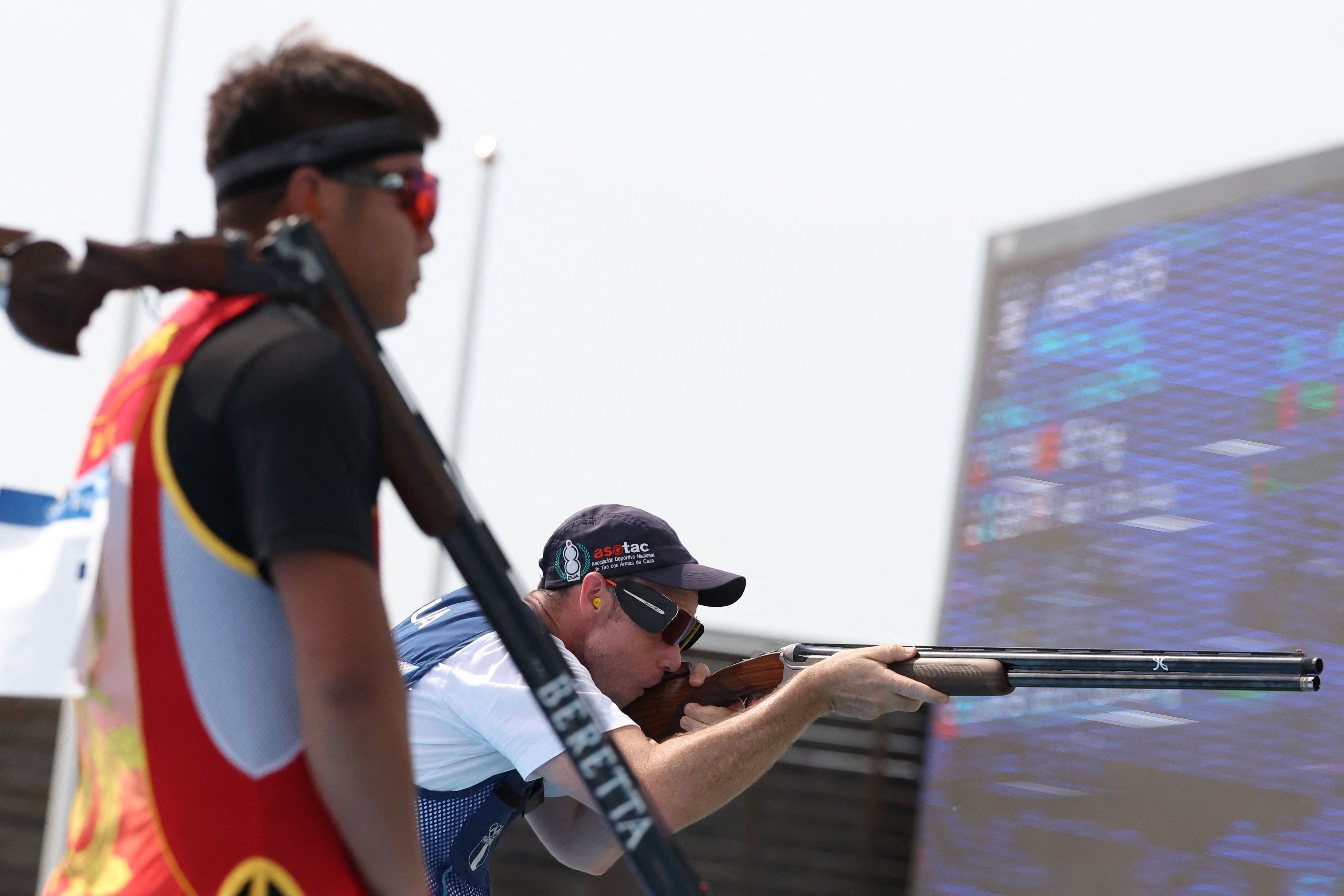 Qi Ying (izq.) de China y Jean Pierre Brol Cárdenas de Guatemala compiten en la final masculina de tiro al plato durante los Juegos Olímpicos de París 2024.'