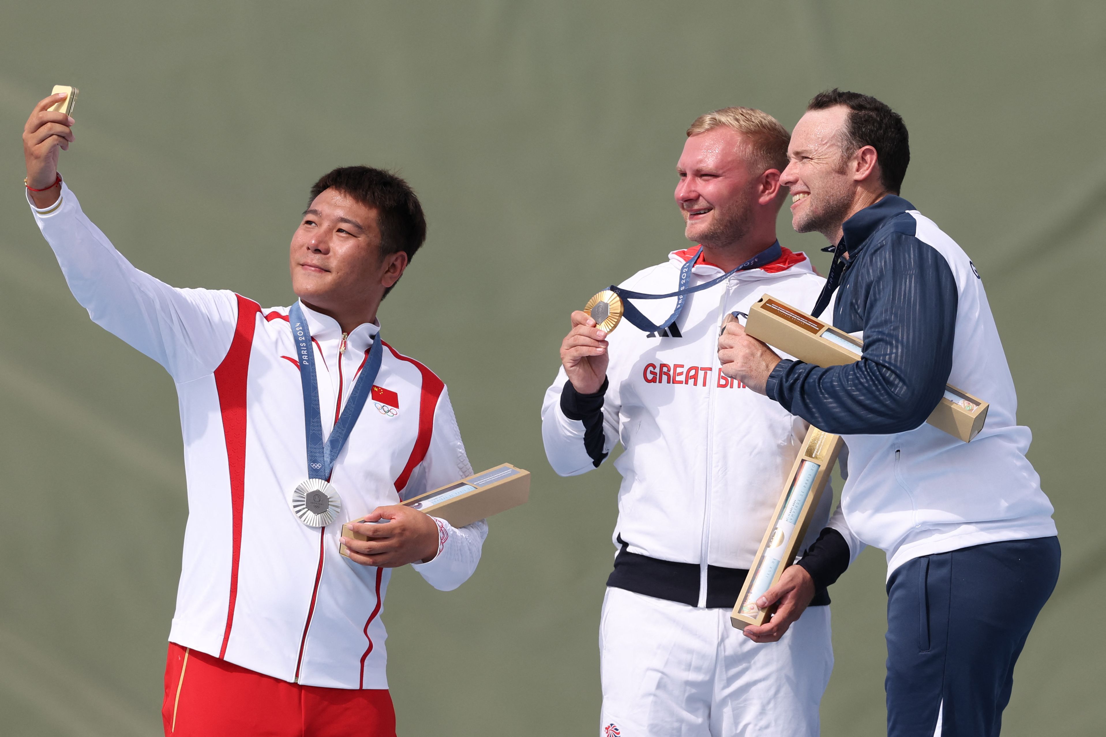 Qi Ying (izquierda) tomando una selfie junto a Nathan Hales (centro) y Jean Pierre Brol (derecha) en el podio.