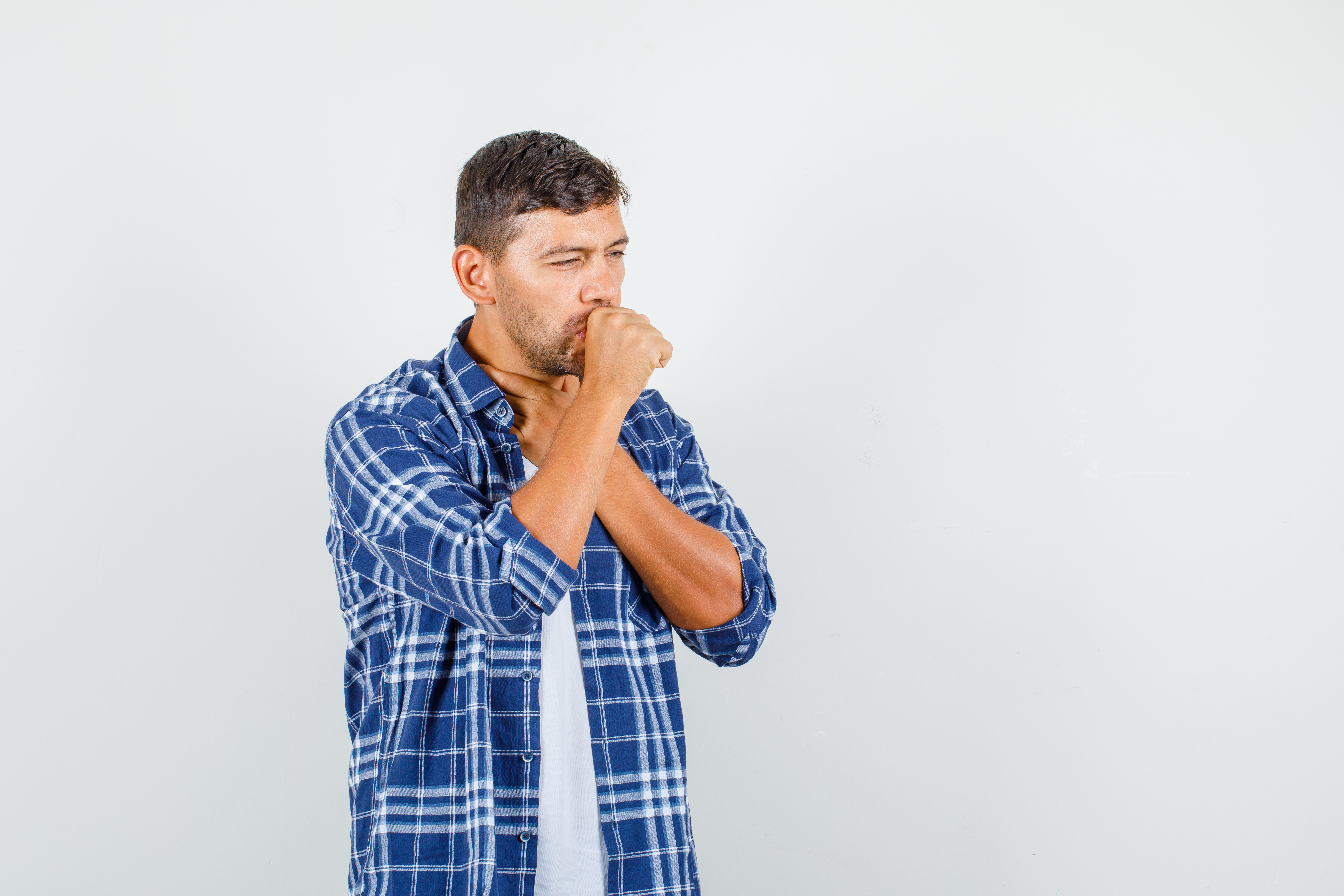 Young man in shirt suffering from cough and looking ill , front view.