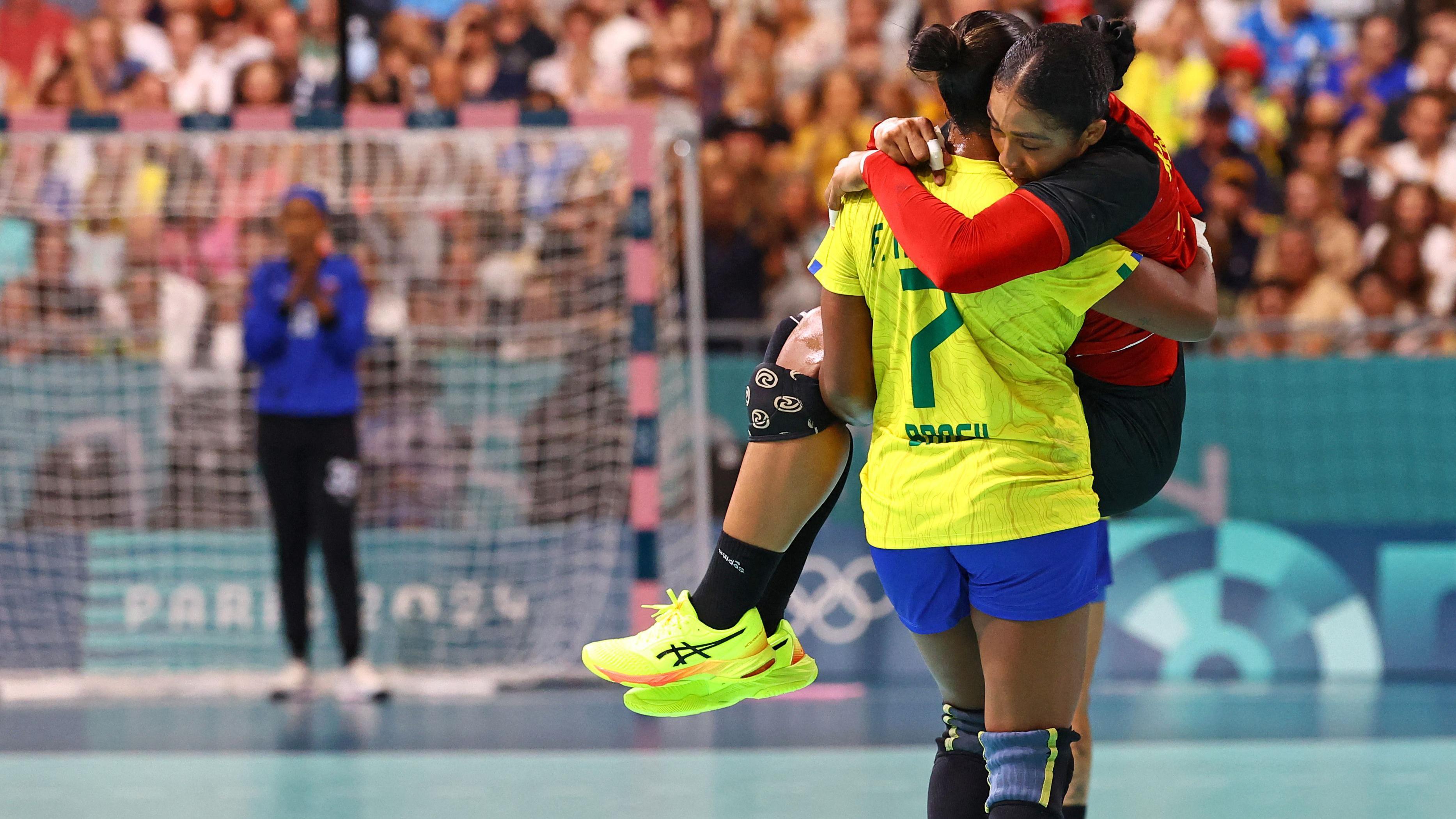 Tamires Araujo de Brasil lleva en brazos a su rival Albertina Kassoma de Angola, durante un partido de balonmano en París 2024. 

Reuters
