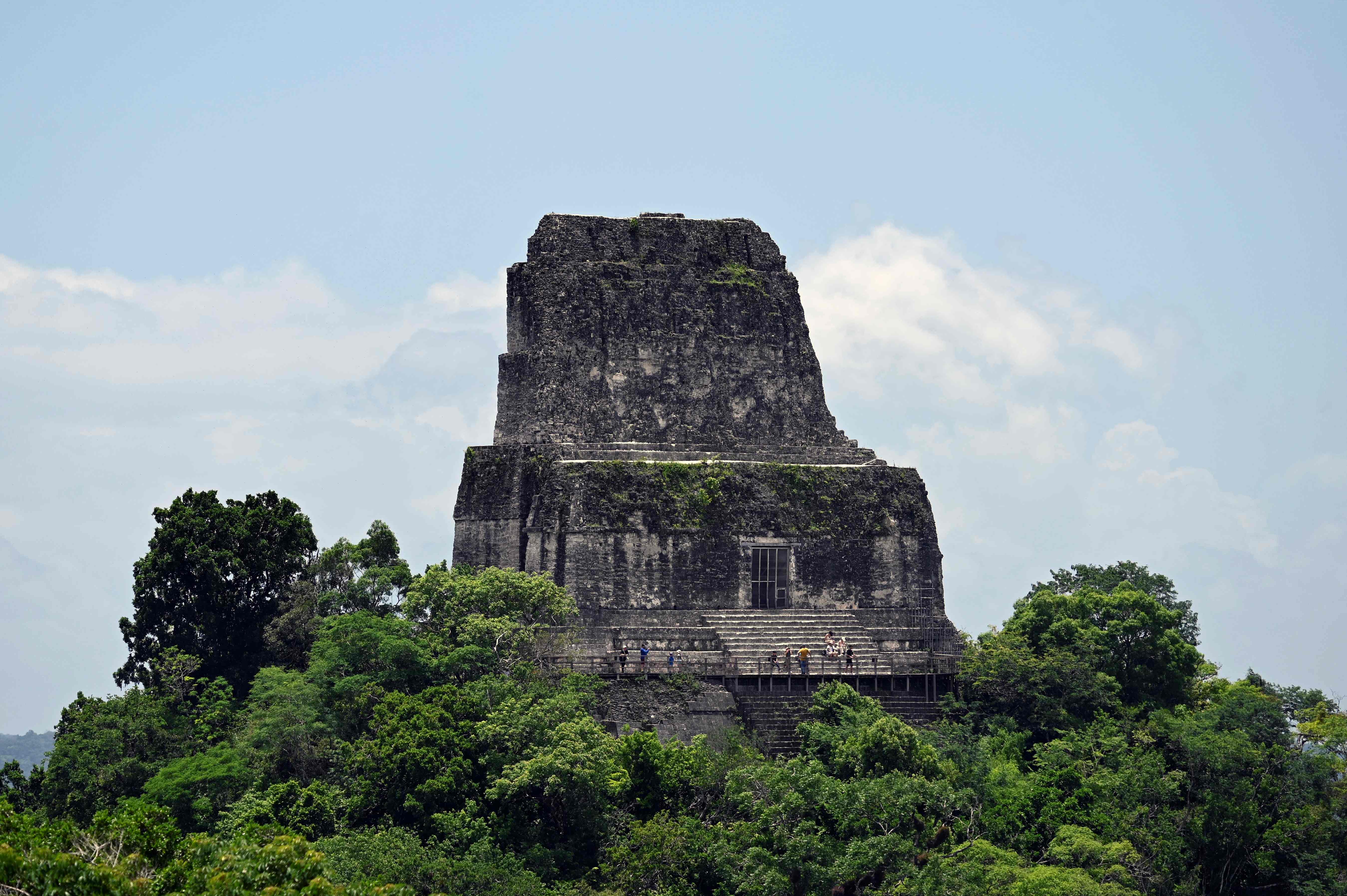 Tourists visit a Mayan temple in the Tikal archaeological site at the Maya Biosphere in Peten, Guatemala on July 24, 2024. In the Mayan jungle of northern Guatemala, thirty leaders from the Colombian Amazon are learning and sharing with Guatemalan farmers a sustainable model to live off the forest without destroying it, which has been in place for three decades in the largest protected area of Central America. (Photo by JOHAN ORDONEZ / AFP)