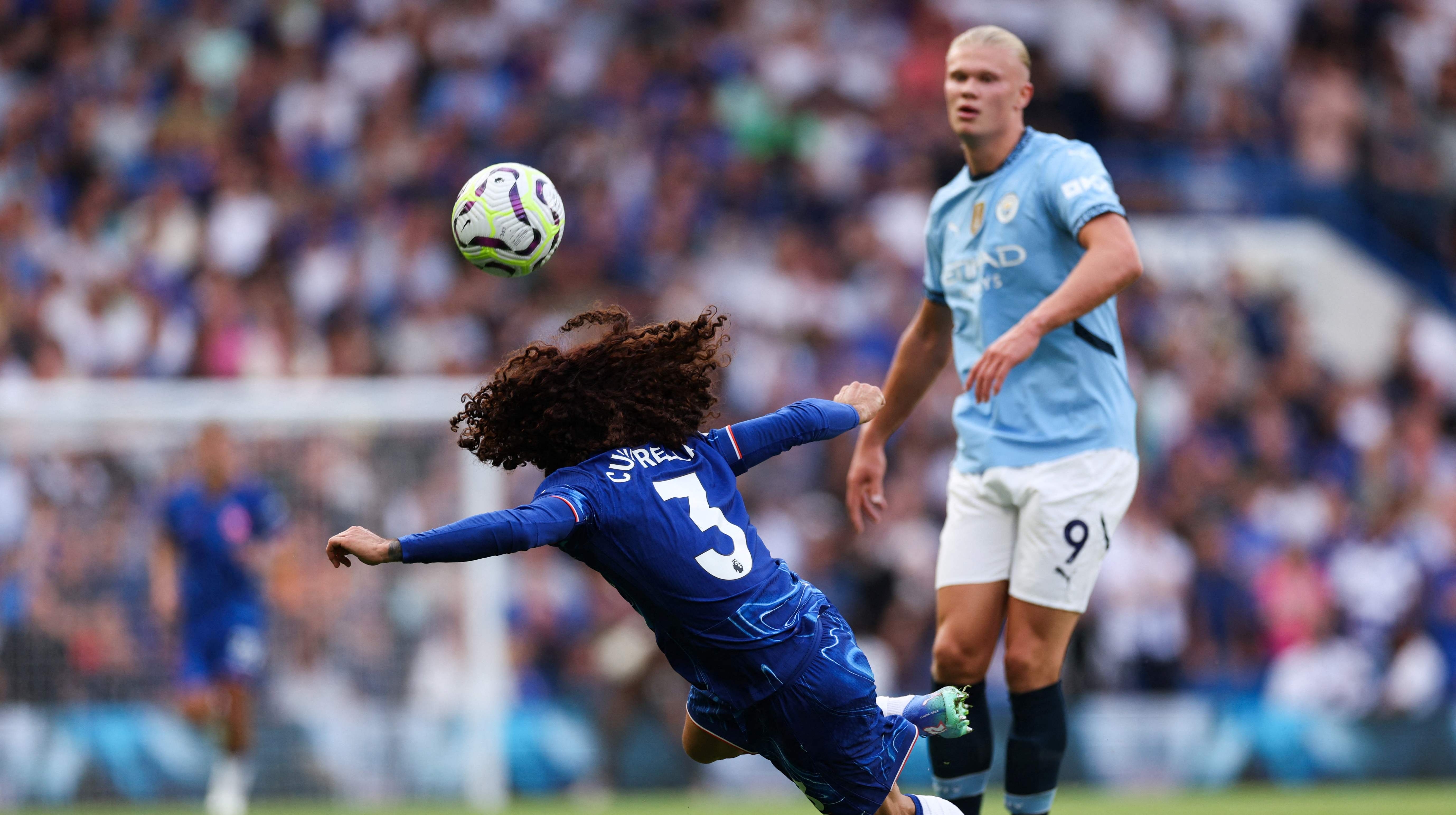 El defensa español del Chelsea Marc Cucurella cabecea el balón frente al delantero noruego del Manchester City Erling Haaland.