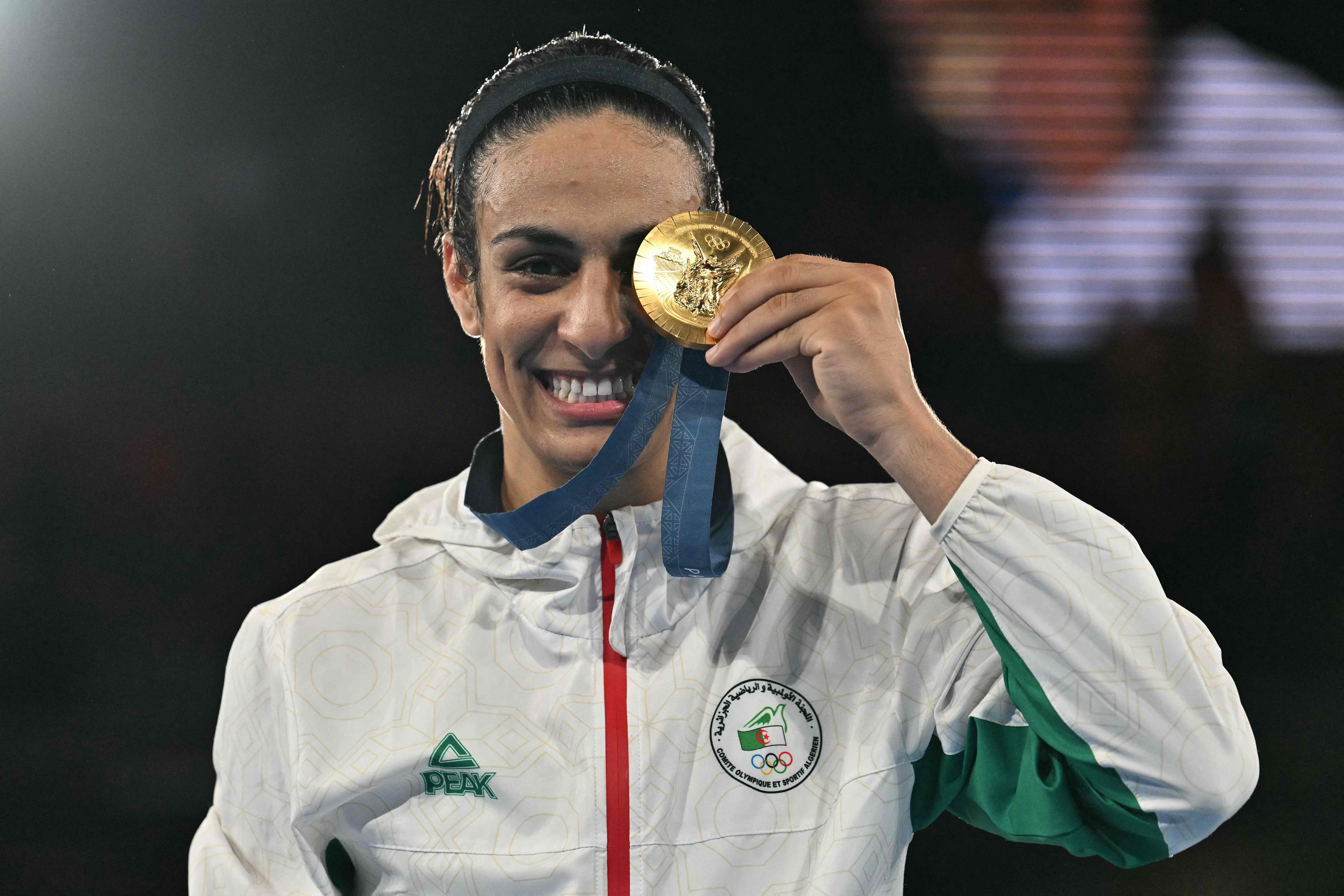 (FILES) Gold medallist Algeria's Imane Khelif poses on the podium during the medal ceremony for the women's 66kg final boxing category during the Paris 2024 Olympic Games at the Roland-Garros Stadium, in Paris on August 9, 2024. The Paris prosecutor's office announced on August 14, 2024, having opened an investigation after Algerian Olympic boxing champion Imane Khelif filed a complaint regarding cyber-harassment. (Photo by MOHD RASFAN / AFP)