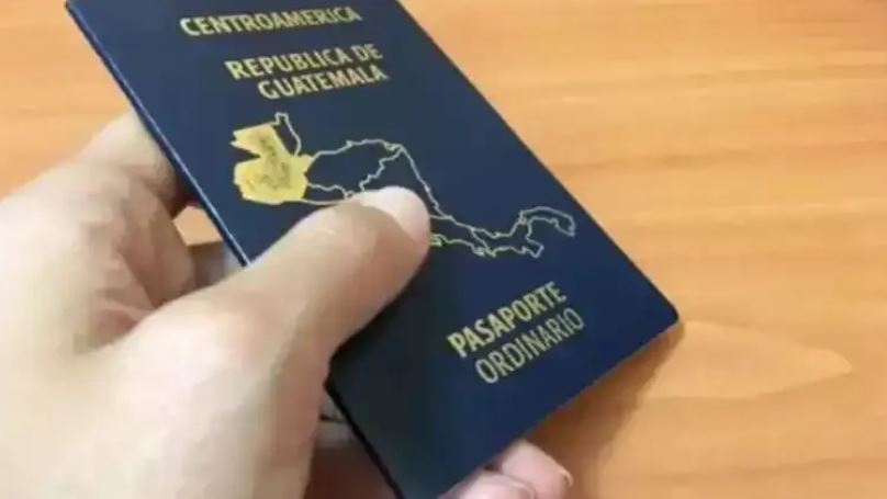 La mano de una persona sosteniendo un pasaporte guatemalteco.