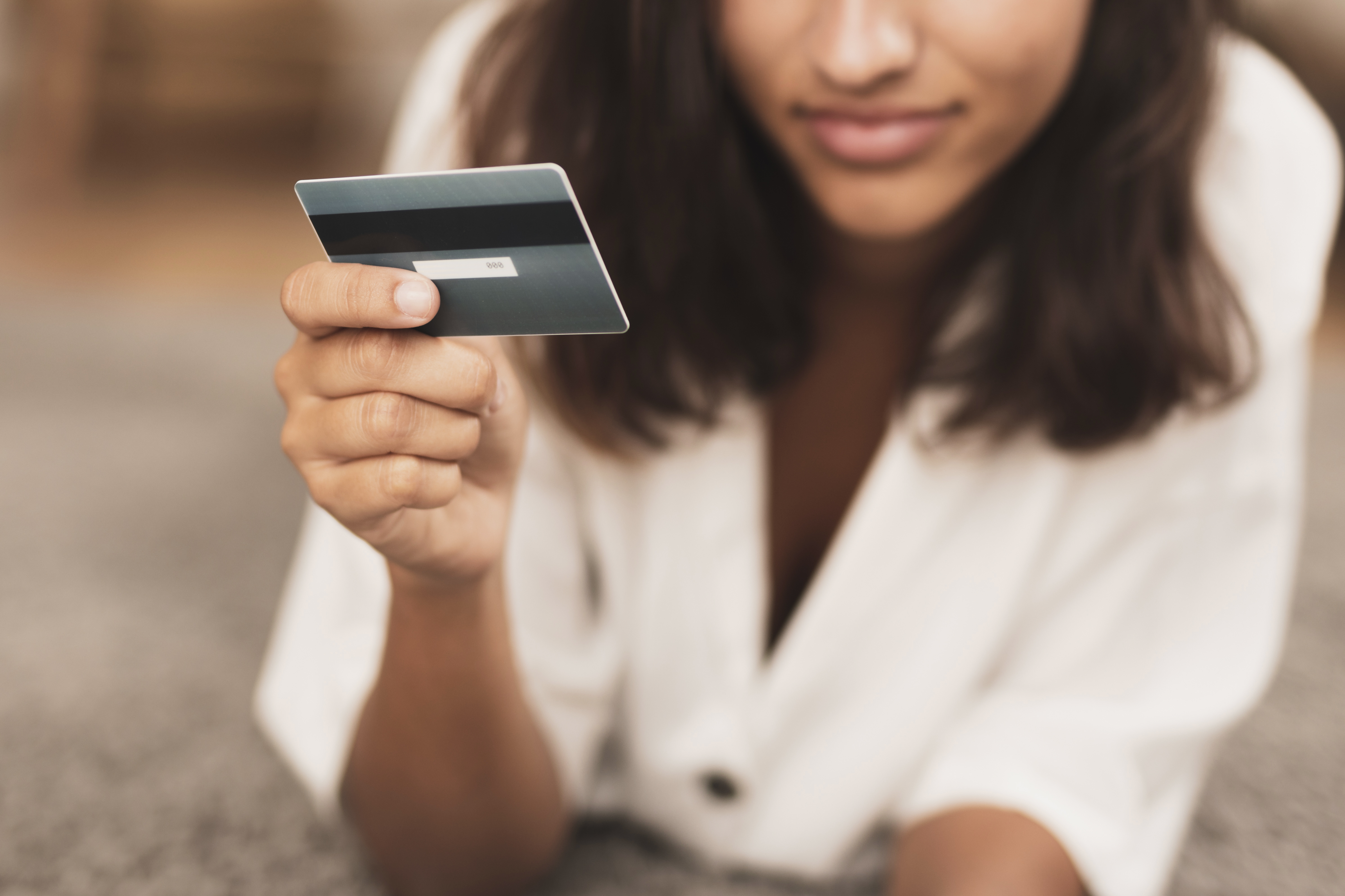 mujer sostiene con la mano derecha una tarjeta de crédito