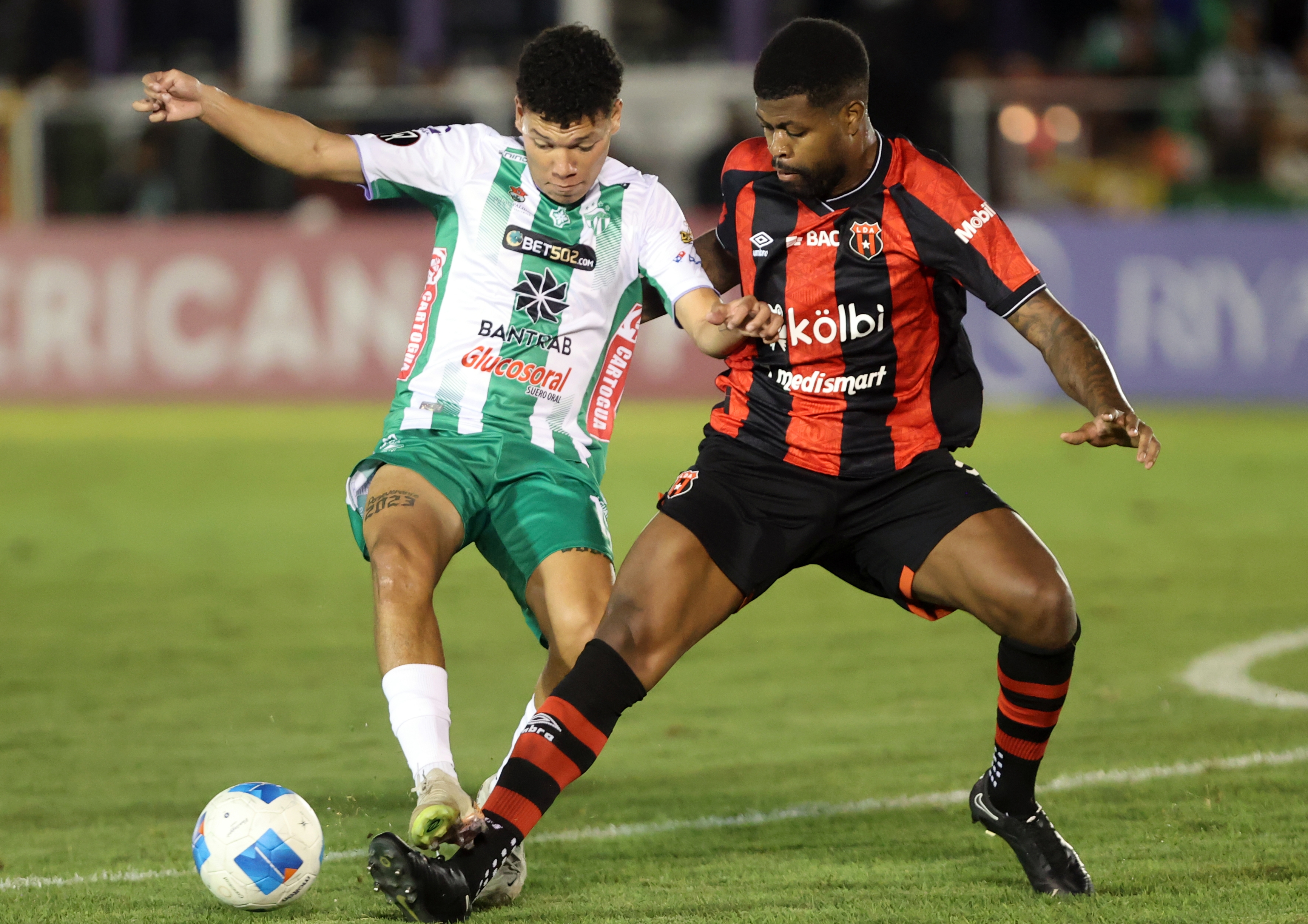 Manjrekar James de Liga Deportiva Alajuelense disputa el balón con José Espinoza de Antigua GFC.