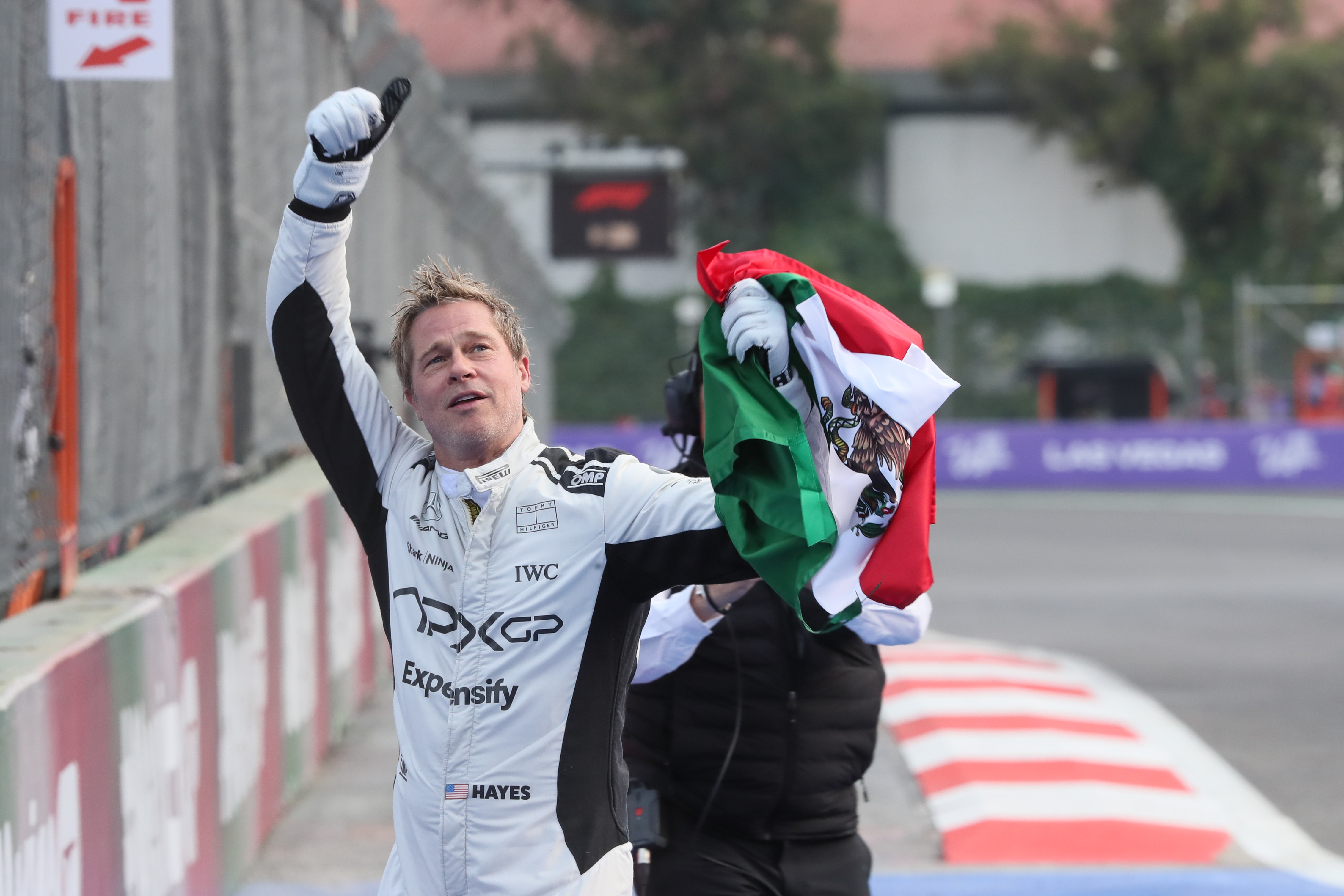 El actor estadounidense Brad Pitt saluda a seguidores con una bandera de México en el Autódromo de los Hermanos Rodríguez en Ciudad de México. (Foto Prensa Libre: EFE)