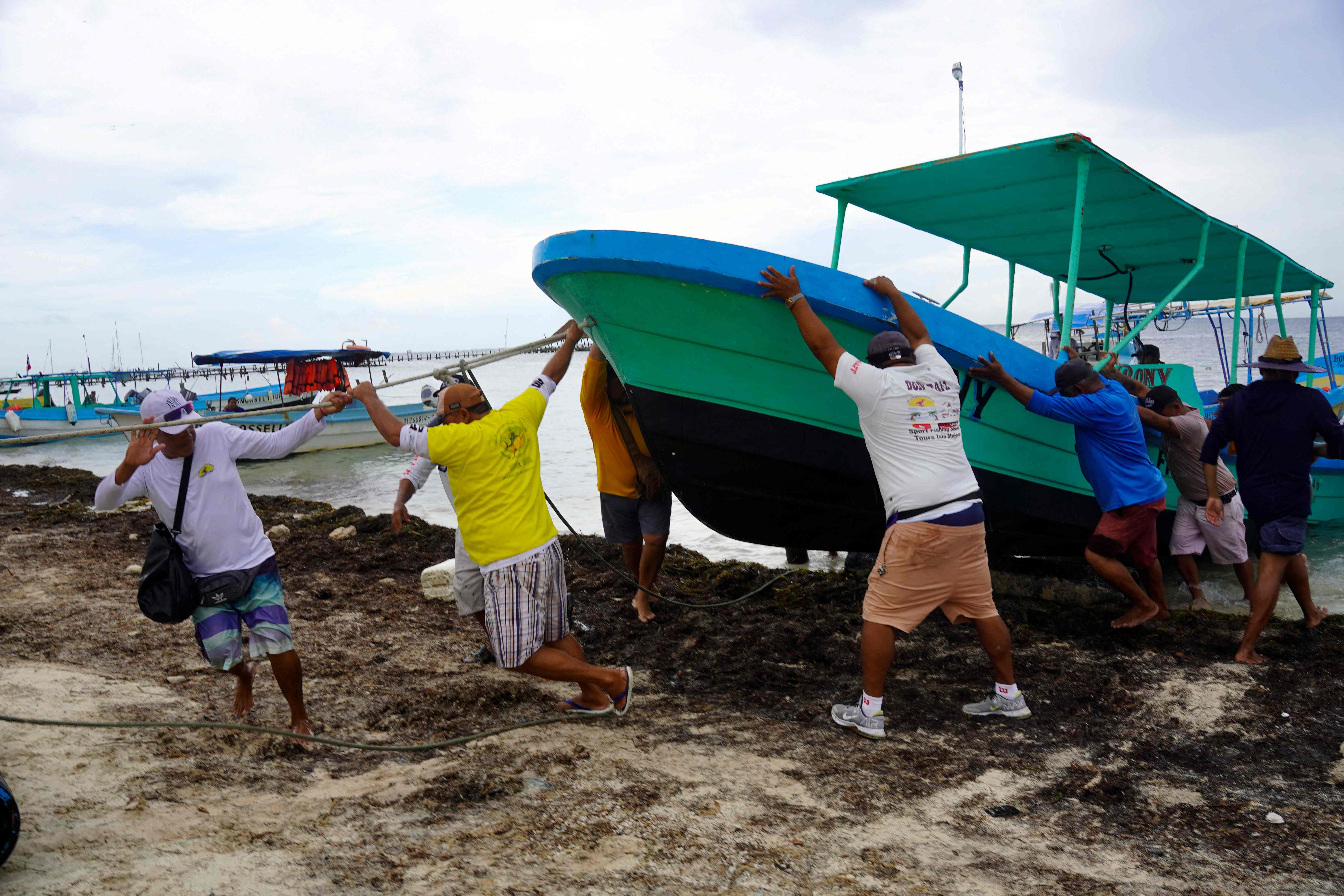 Pescadores y trabajadores turísticos sacan sus barcos del mar como medida de precaución antes del paso del huracán Milton.