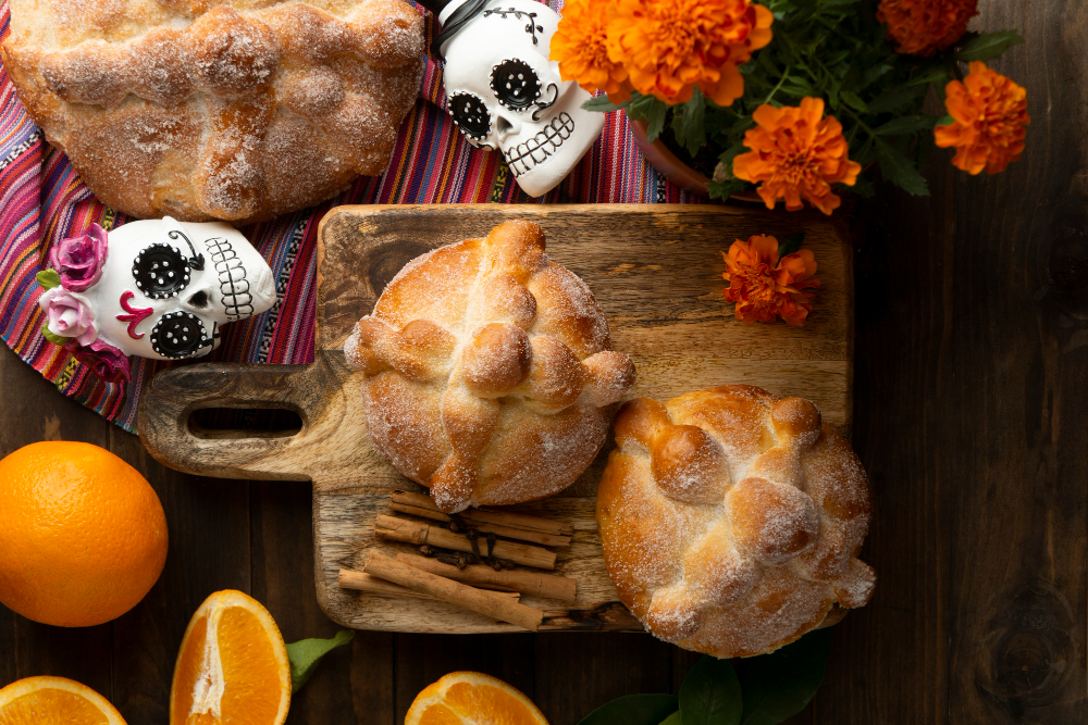 Pan de muerto acompañado de flores y otros detalles.