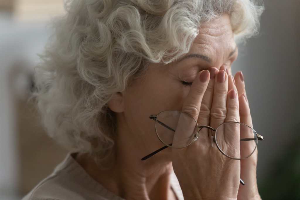 Cierre de la sesión de mujeres ancianas cansadas frotar los ojos de masaje quitarse los vasos que padecen dolor de cabeza o migraña, hembras de 60 años exhaustas tienen mareos o visión borrosa de la presión arterial alta