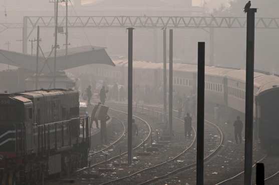 Passengers wait for their trains at a railway station engulfed in smog in Lahore on November 22, 2024. (Photo by Arif ALI / AFP)